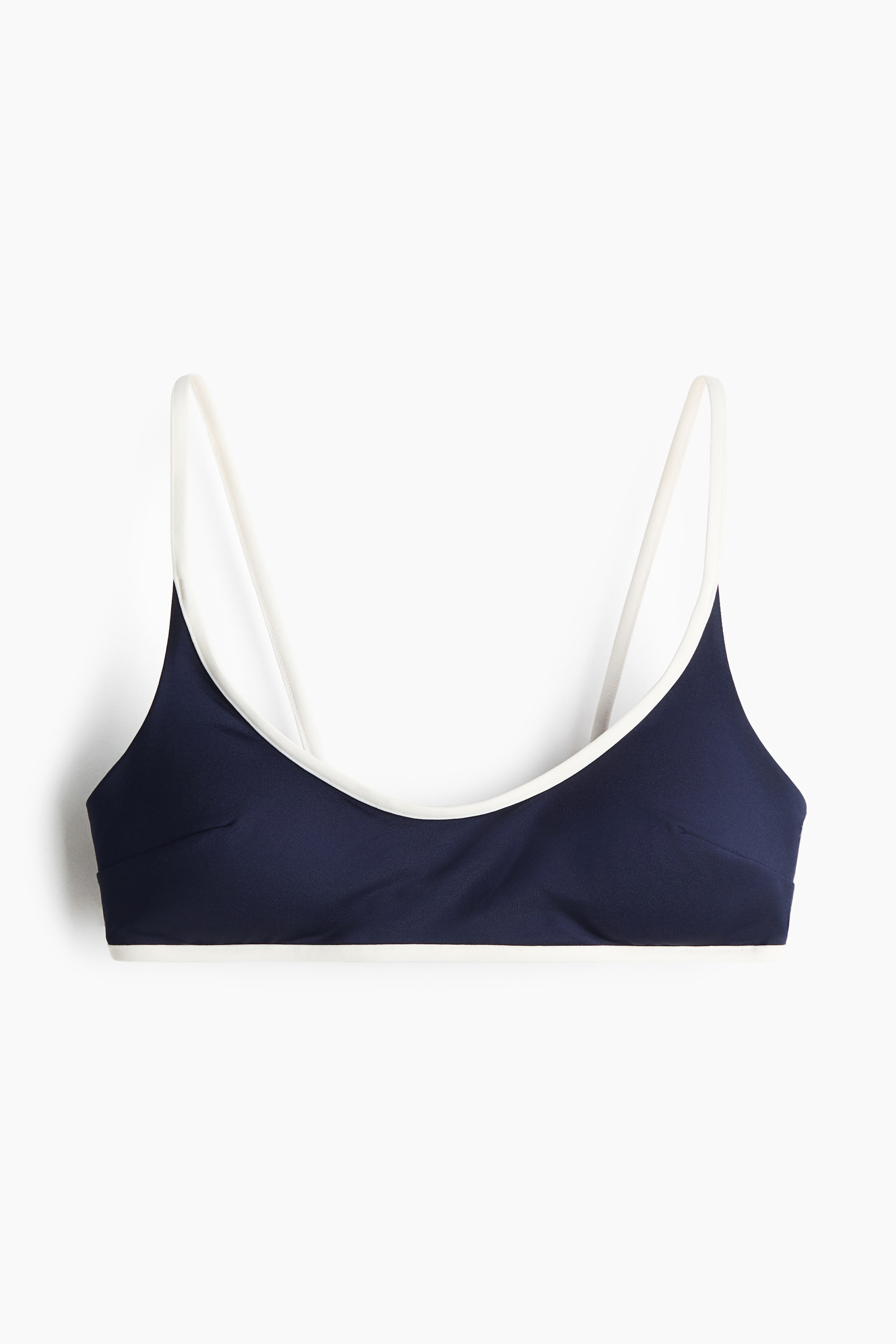 View larger image: The front view of a navy blue bikini top is displayed, accentuated by slender white shoulder straps. The neckline and bottom band are elegantly outlined with white trim.