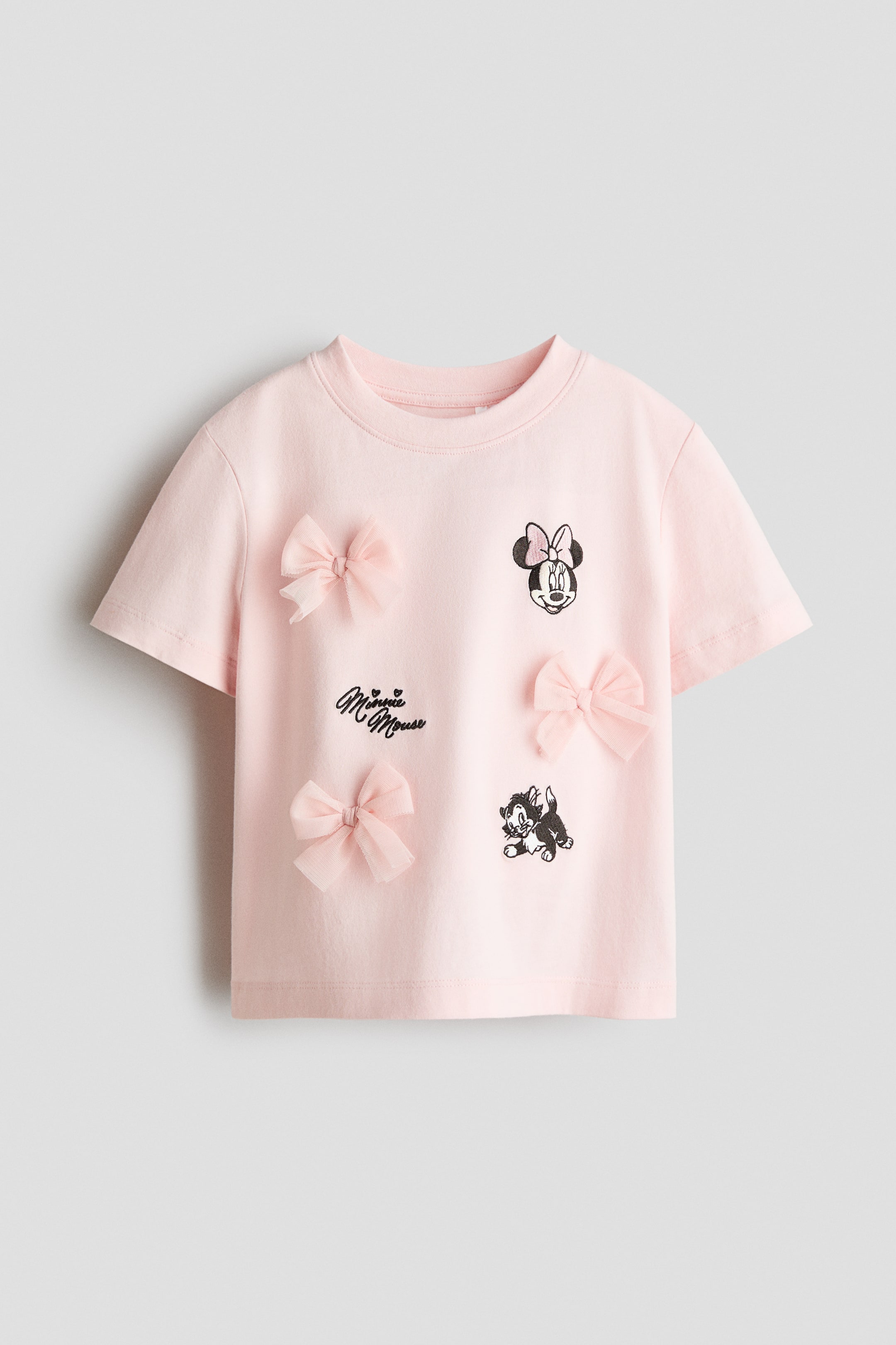 Voir une image plus grande: Un T-shirt rose présente un col rond et des manches courtes sur le DEVANT, avec des motifs imprimés de la tête de Minnie Mouse, le texte "Minnie Mouse", et un petit chat noir et blanc, accompagnés de quatre nœuds roses en tulle appliqués sur le devant.