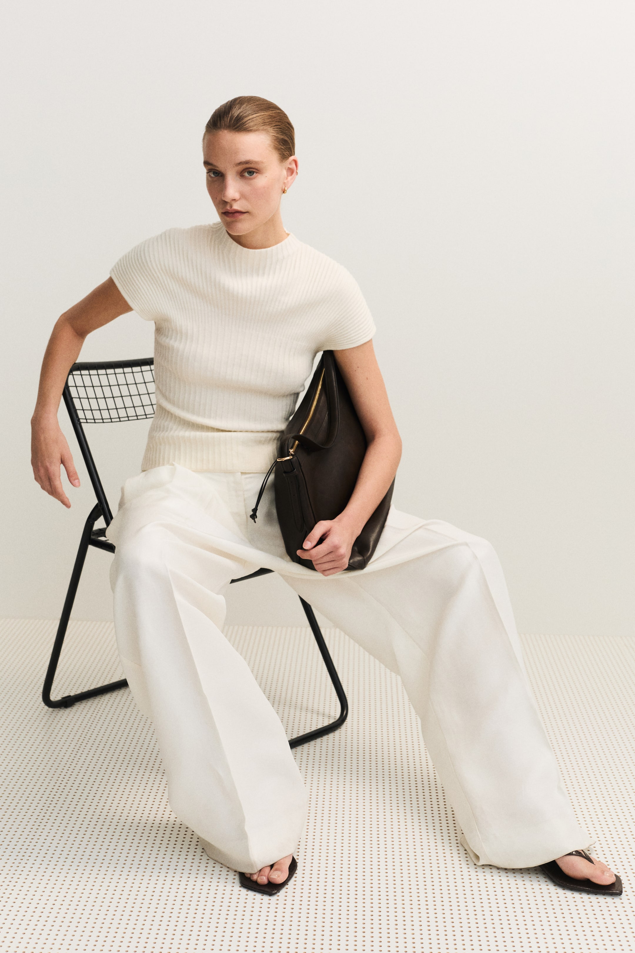 View larger image: The cream-colored fitted top is shown from the front, highlighting its soft rib knit texture. It features a small stand collar and short sleeves.