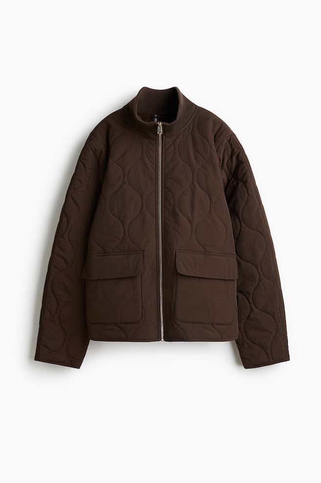 A dark brown onion-quilted jacket is presenting its front. It is featuring a ribbed stand-up collar, a silver-toned front zipper closure, and two large flap patch pockets on the lower front. - 1