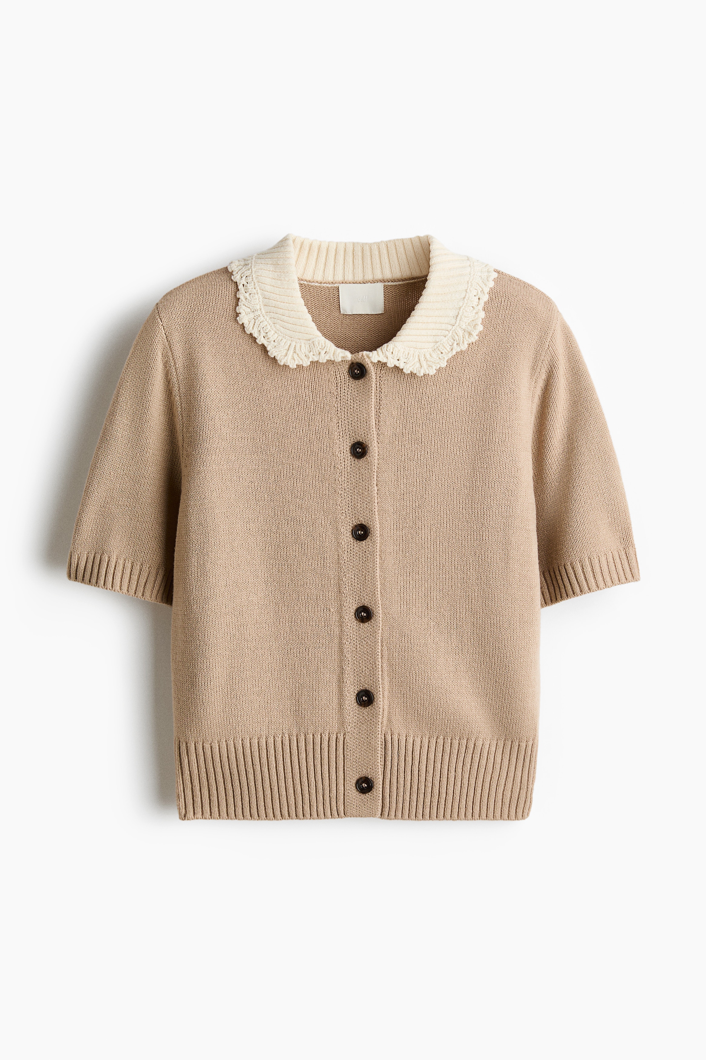 NgÆ°á»i máº«u Äang máº·c má»t chiáº¿c Ã¡o cardigan dá»t kim tay ngáº¯n mÃ u be, ÄÆ°á»£c phá»i cÃ¹ng quáº§n sÃ¡ng mÃ u. Ão cardigan cÃ³ cá» trÃ²n mÃ u kem tÆ°Æ¡ng pháº£n vá»i viá»n dá»t kim cÃ³ káº¿t cáº¥u, cÃºc cÃ i phÃ­a trÆ°á»c mÃ u sáº«m, cÃ¹ng bo tay Ã¡o vÃ  gáº¥u Ã¡o dá»t gÃ¢n.
