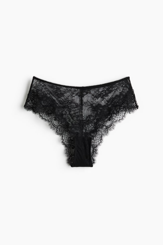 Schwarze Spitzen-Slips liegen flach und präsentieren filigrane florale Spitzenmuster sowie gewellte Kanten entlang der Taille und Beinausschnitte. - 1