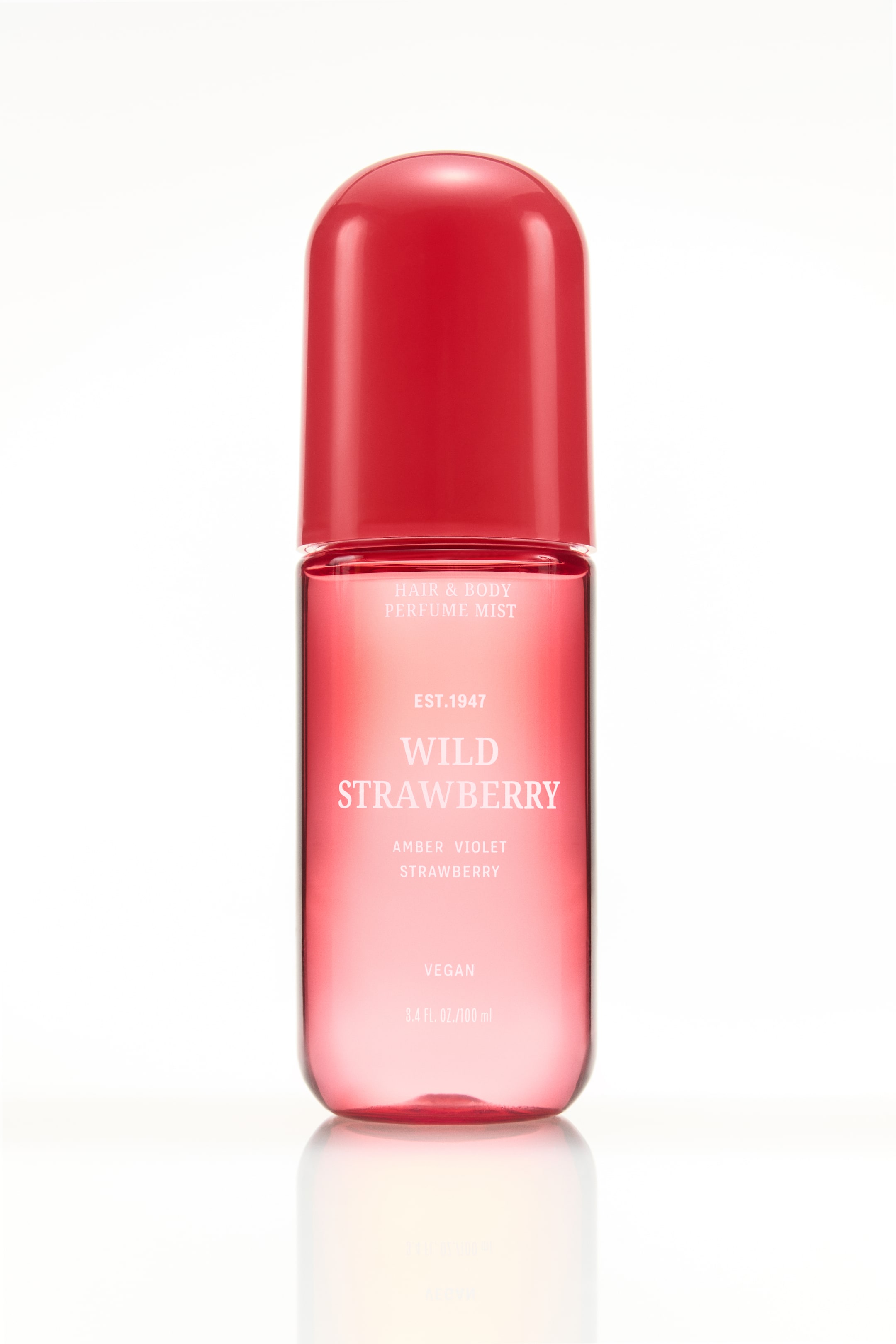 Agrandir l'image: Un flacon de brume parfumée pour cheveux et corps est posé debout, avec un bouchon rond rouge solide et un corps rose translucide. L'étiquette affiche "Brume Parfumée Cheveux & Corps", "Fraise Sauvage", "Violette Ambrée Fraise", "Vegan" et "3,4 fl. oz./100 ml" en texte blanc.