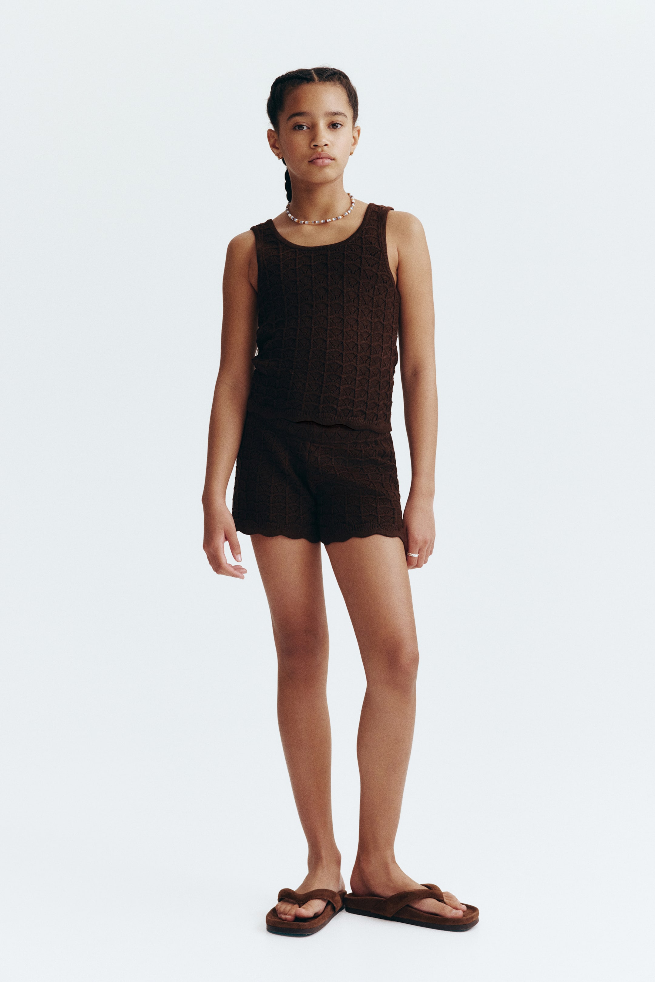 View larger image: Shorts, facing front, are showcasing a dark brown soft pointelle knit, featuring an elasticated waist and scalloped, ribbed trim at the hems.