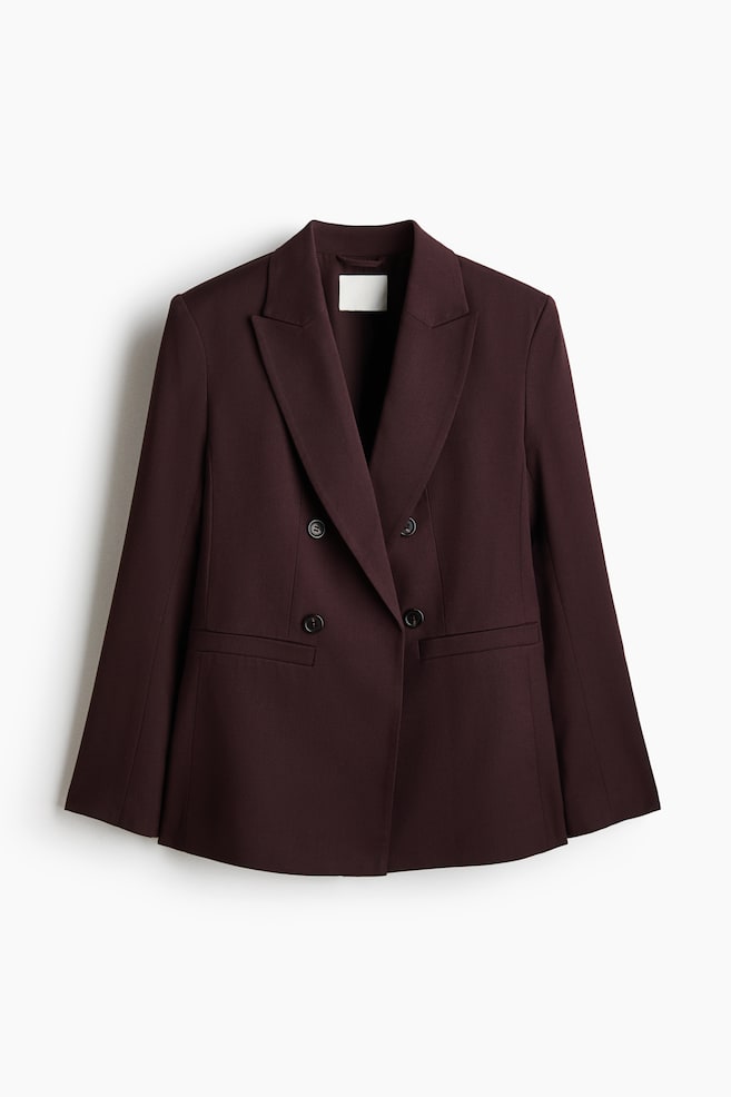A deep burgundy blazer is displaying a double-breasted design with two rows of dark buttons, wide notch lapels, and two flap pockets at the front. - 1