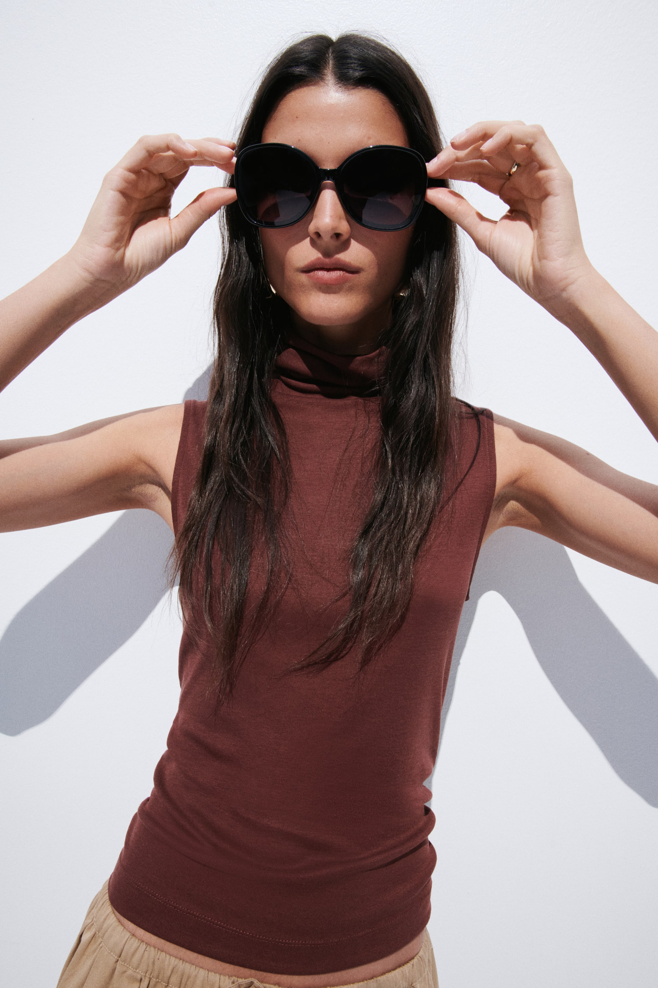 View larger image: The dark reddish-brown sleeveless top is showcased from the front. It features a high turtleneck, a fitted silhouette, and a straight hem, crafted from a smooth, stretchy fabric.