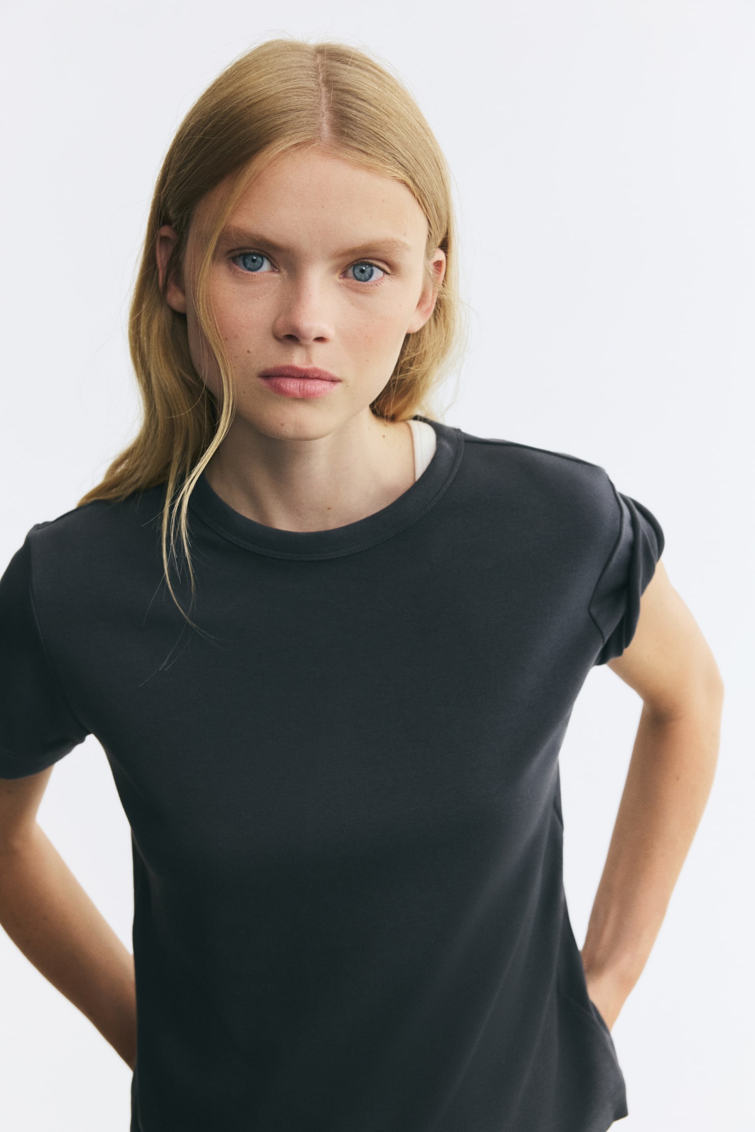 A dark grey fitted t-shirt in heavy cotton jersey is facing forward, showcasing its structure. It features ribbing around the crew neckline and a straight-cut hem. - 1