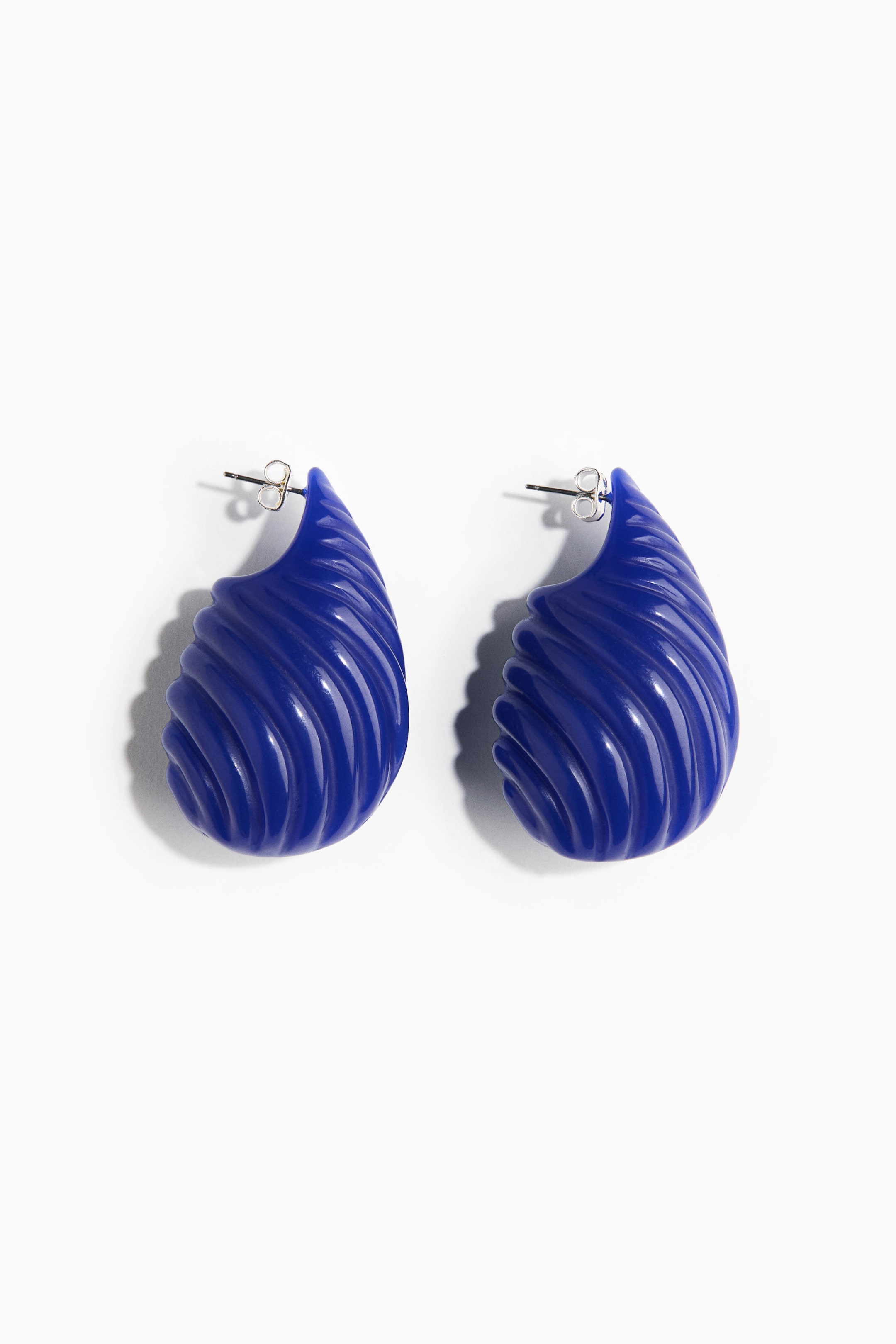 View larger image: Two deep blue earrings showcase a teardrop shape with a swirling, ridged surface texture. Each earring features a silver-toned stud post at its top.