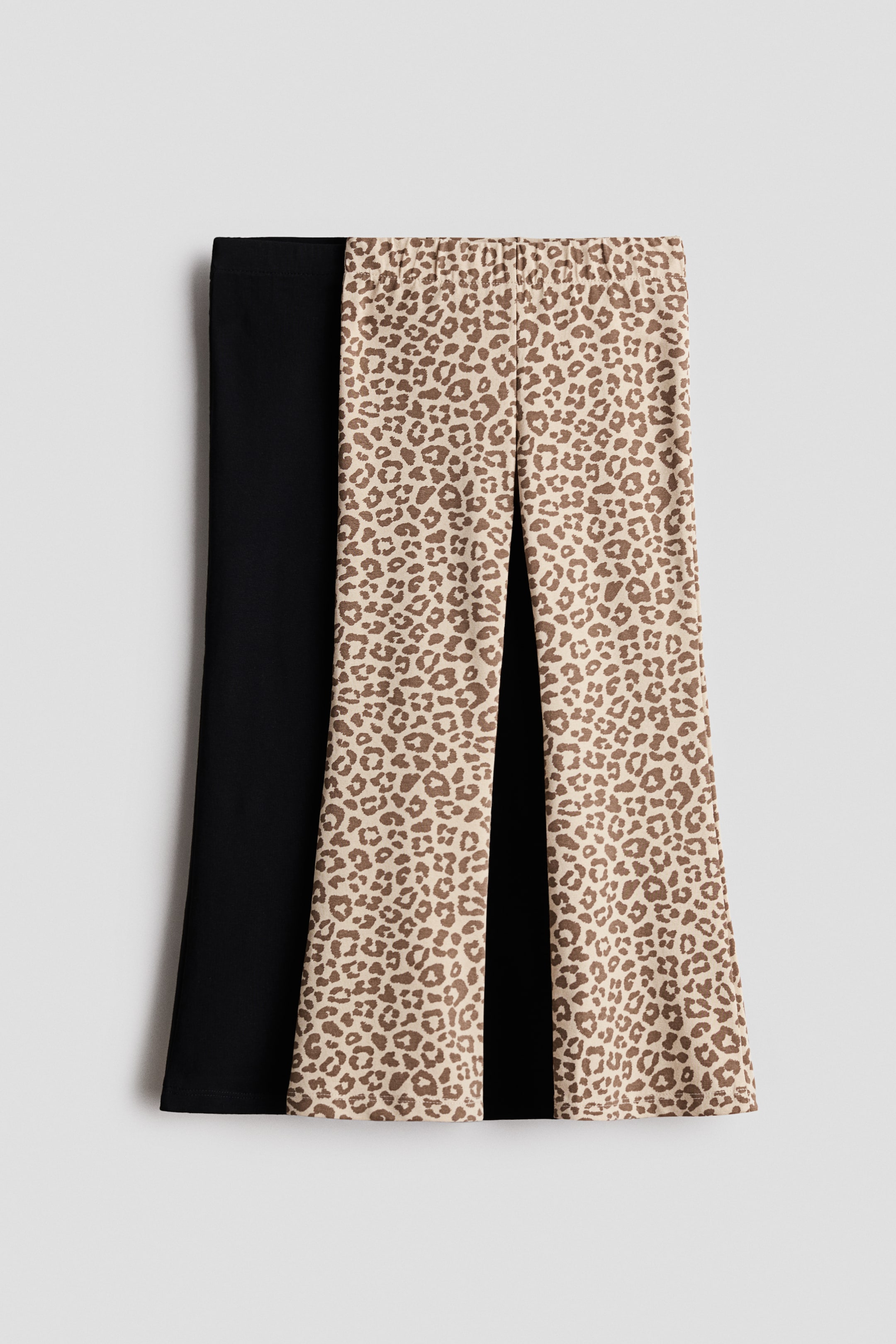 Vis større bilde: To par leggings vises i en flat-lay, frontvendt visning, en i ensfarget svart og en beige med brunt leopardmønster. Begge parene har elastisk midje og utsvingte ben.