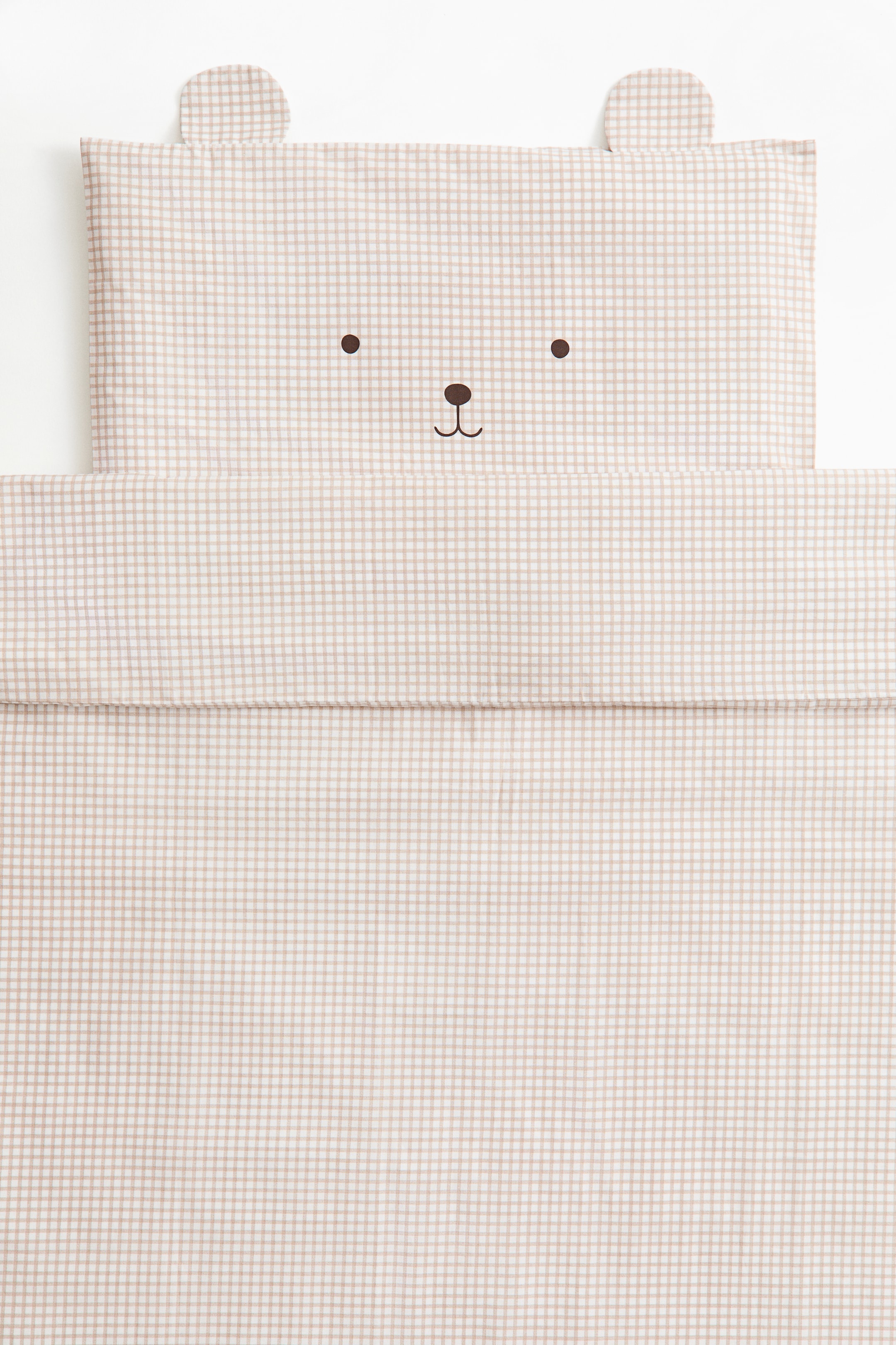Grotere afbeelding bekijken: Deze van voren gefotografeerde kinderdekbedovertrekset toont een beige-wit ginghampatroon, met een kussensloop met een minimalistisch geprint berengezicht en aangehechte stoffen oortjes bovenop, naast een bijpassende opgevouwen dekbedovertrek.