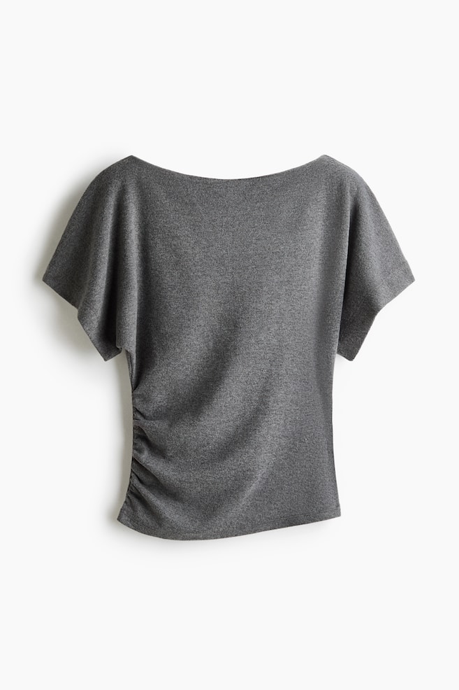 A grey short-sleeved top is shown from the front, featuring a wide boatneck and draped, short dolman sleeves. The lightweight, heathered knit fabric is gathering into a ruched detail along one side seam, creating soft asymmetrical draping across the bodice. - 1