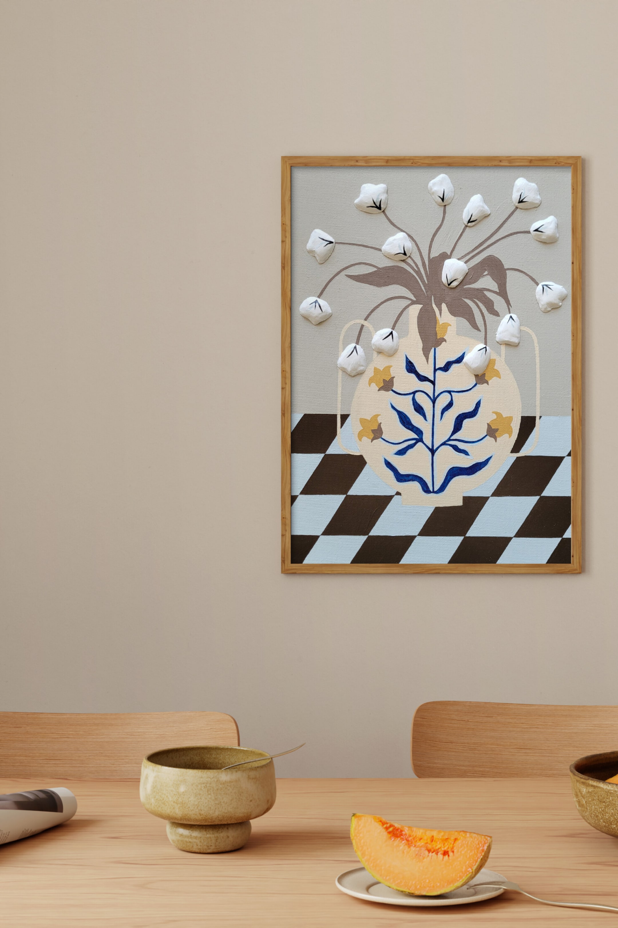 Größeres Bild ansehen: Ein gerahmtes Kunstwerk zeigt eine beigefarbene Vase, verziert mit blauen und gelben Motiven, die stilisierte weiße 3D-Blumen mit braunen Stielen hält. Die Vase steht auf einem hellblau- und dunkelbraun karierten Muster, alles eingefasst in einen natürlichen Holzrahmen und direkt nach vorne ausgerichtet.