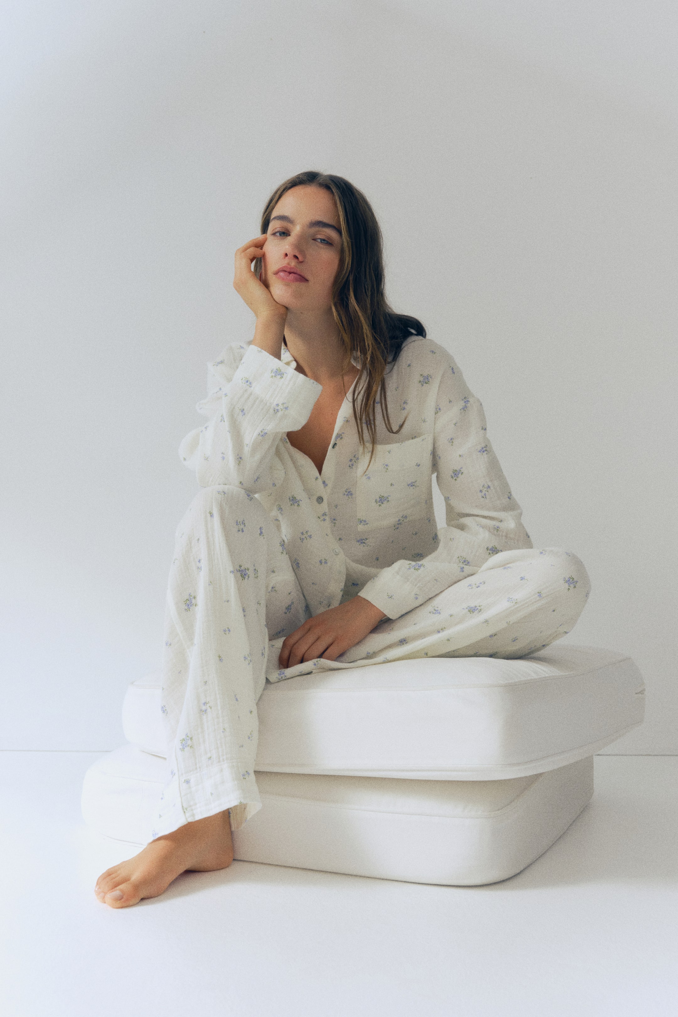 View larger image: White soft cotton muslin pyjamas with a blue floral print, featuring a shirt with a collar, front button fastening, a patch chest pocket, dropped shoulders, and long sleeves. The matching bottoms are designed with an elasticated waist and straight legs.