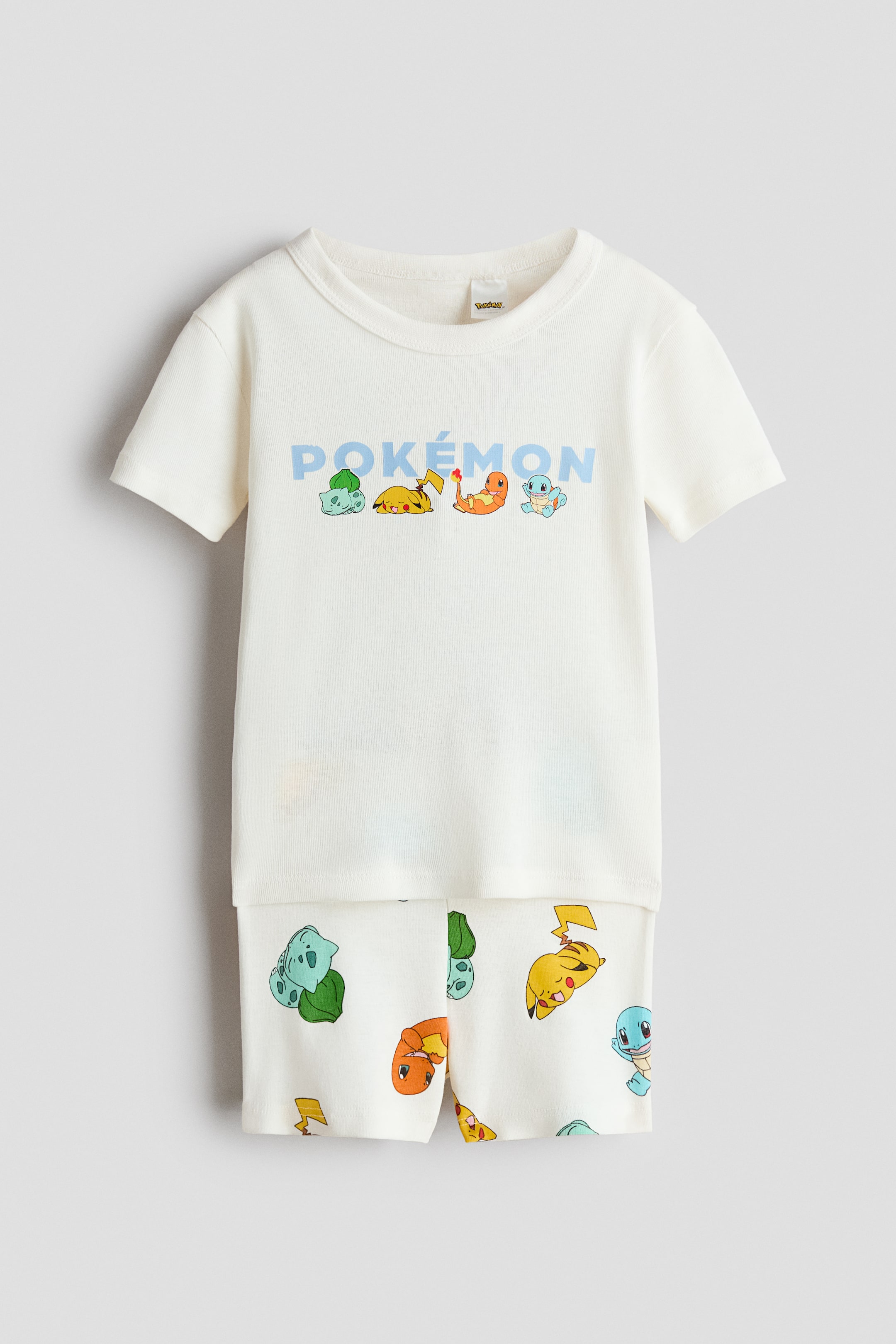 View larger image: Front: A pajama T-shirt and shorts set in soft cotton jersey. The off-white T-shirt features a light blue POKÉMON graphic with Bulbasaur, Pikachu, Charmander, and Squirtle, while the coordinating shorts have an all-over print of the same characters and lightning bolts and an elastic waistband.