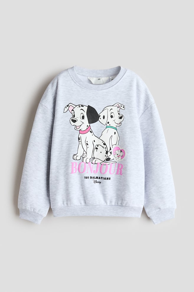 Se muestra de frente una sudadera jaspeada en gris claro, con cuello redondo, hombros caÃ­dos y mangas largas con puÃ±os acanalados. La parte delantera de la sudadera presenta un grÃ¡fico impreso de dos dÃ¡lmatas de dibujos animados sobre la palabra "BONJOUR" en letras rosas, y remate con bajo acanalado. - 1