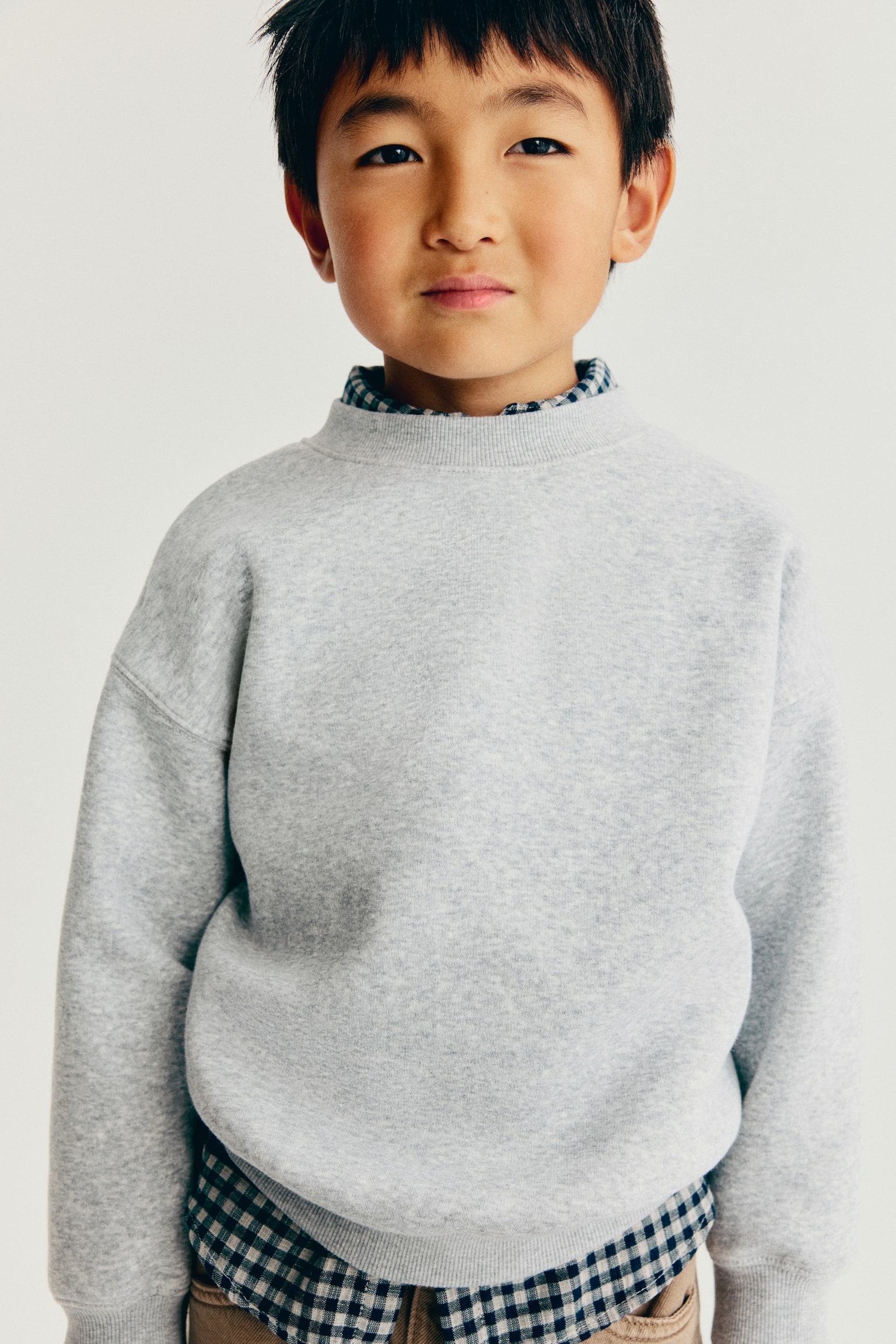 A light grey sweatshirt is showcased from the front, featuring a ribbed crew neck, long sleeves with ribbed cuffs, and a ribbed hem. - 1
