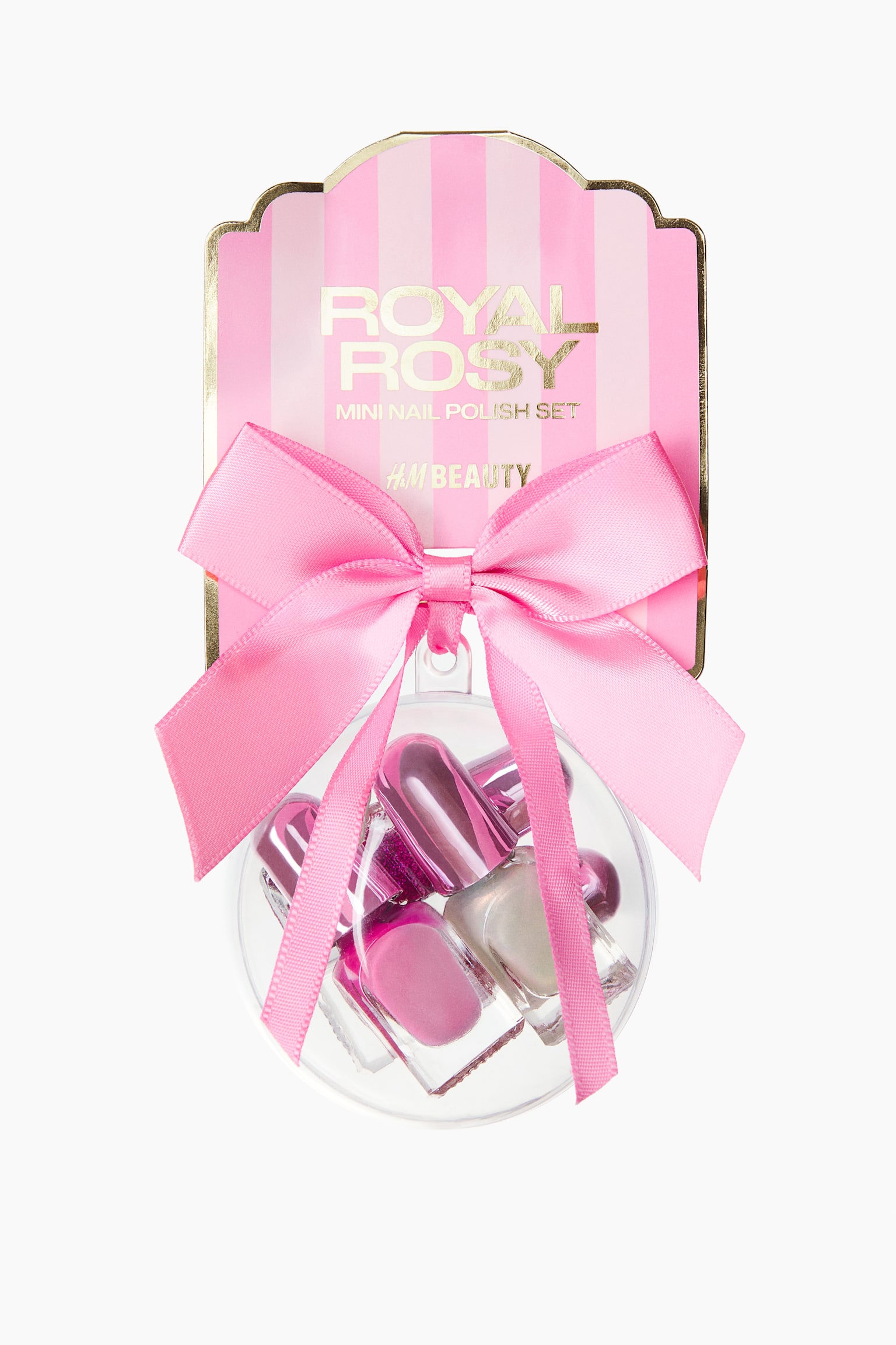 A mini nail polish set is shown from the front, featuring four small nail polish bottles with metallic pink caps and shimmering finishes enclosed within a clear spherical bauble. The bauble is attached to a pink-and-white striped backing card with gold lettering and is decorated with a large, bright pink satin bow.