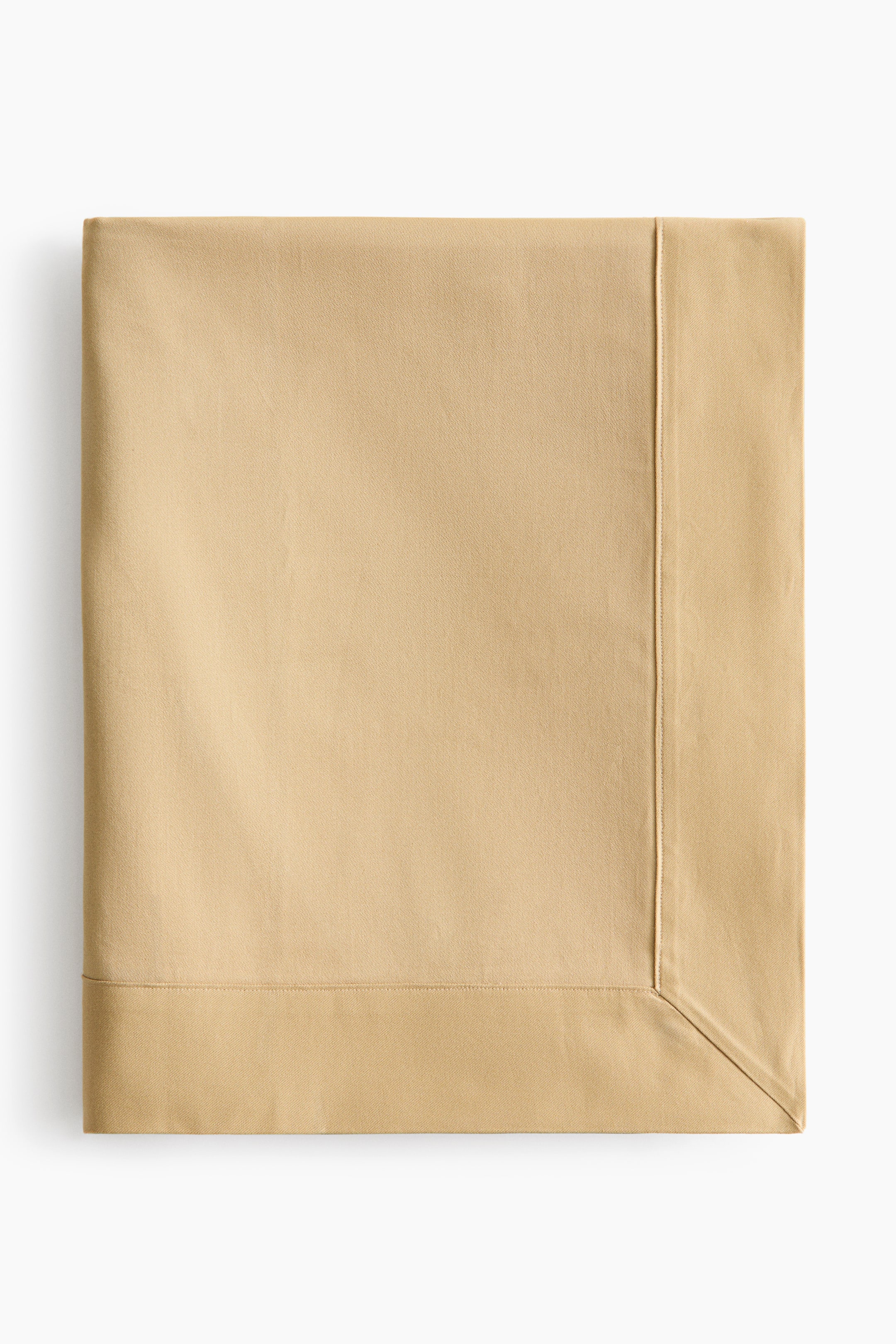 View larger image: A light tan tablecloth is neatly folded, with stitched hems along the edges and a mitred corner visible at the bottom right.