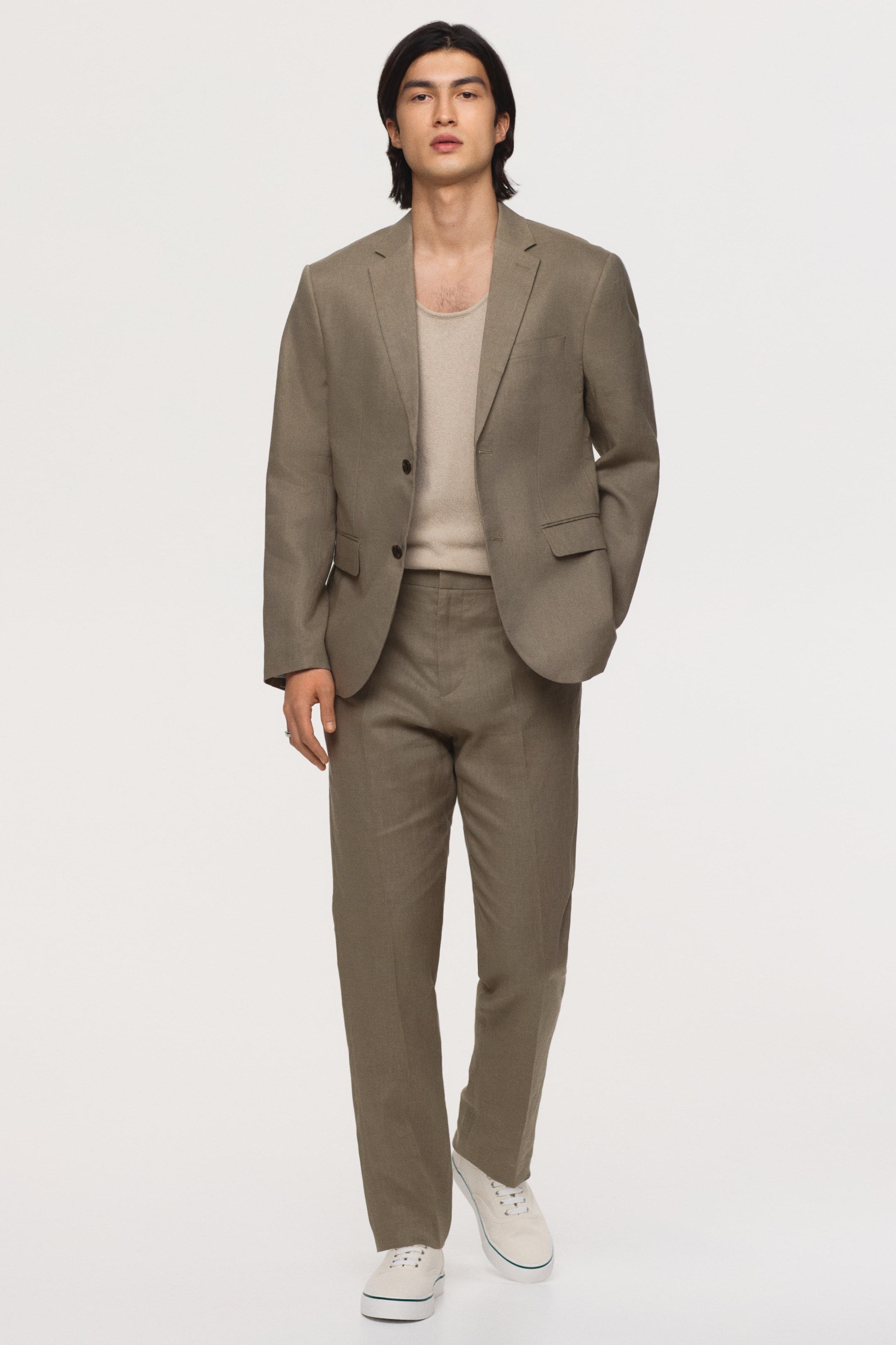 View larger image: The model is wearing light brown, airy linen suit trousers. They showcase visible leg creases and a slim fit, completing a coordinated suit ensemble.