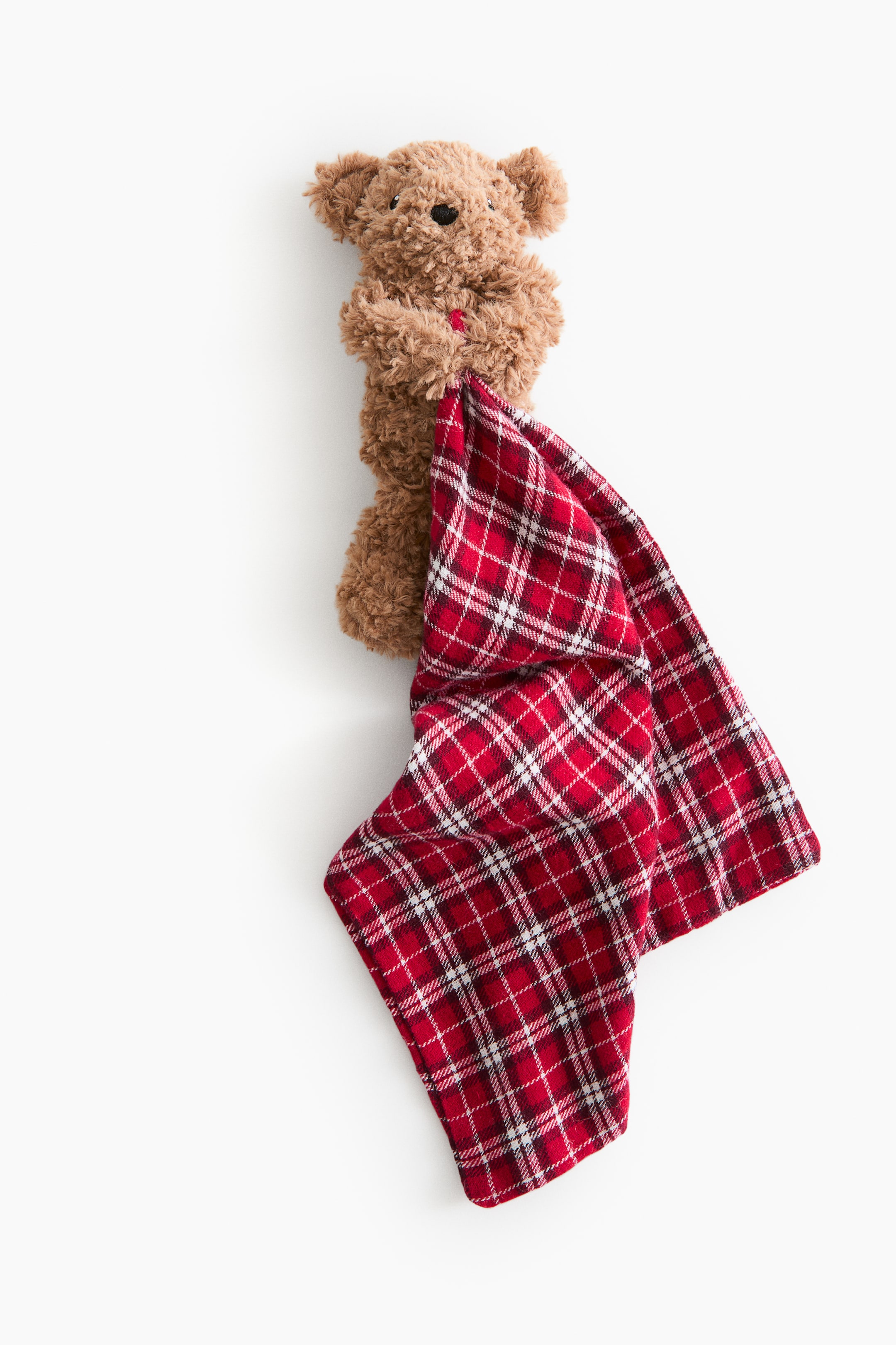 Ampliar la imagen: Una manta de apego con osito de peluche muestra su parte frontal, con la cabeza y la parte superior del cuerpo de un osito de peluche de felpa color café, con nariz y ojos negros. Sus brazos parecen sostener una manta de cuadros rojos y blancos, que presenta un patrón de rojo con líneas blancas y delgadas negras.