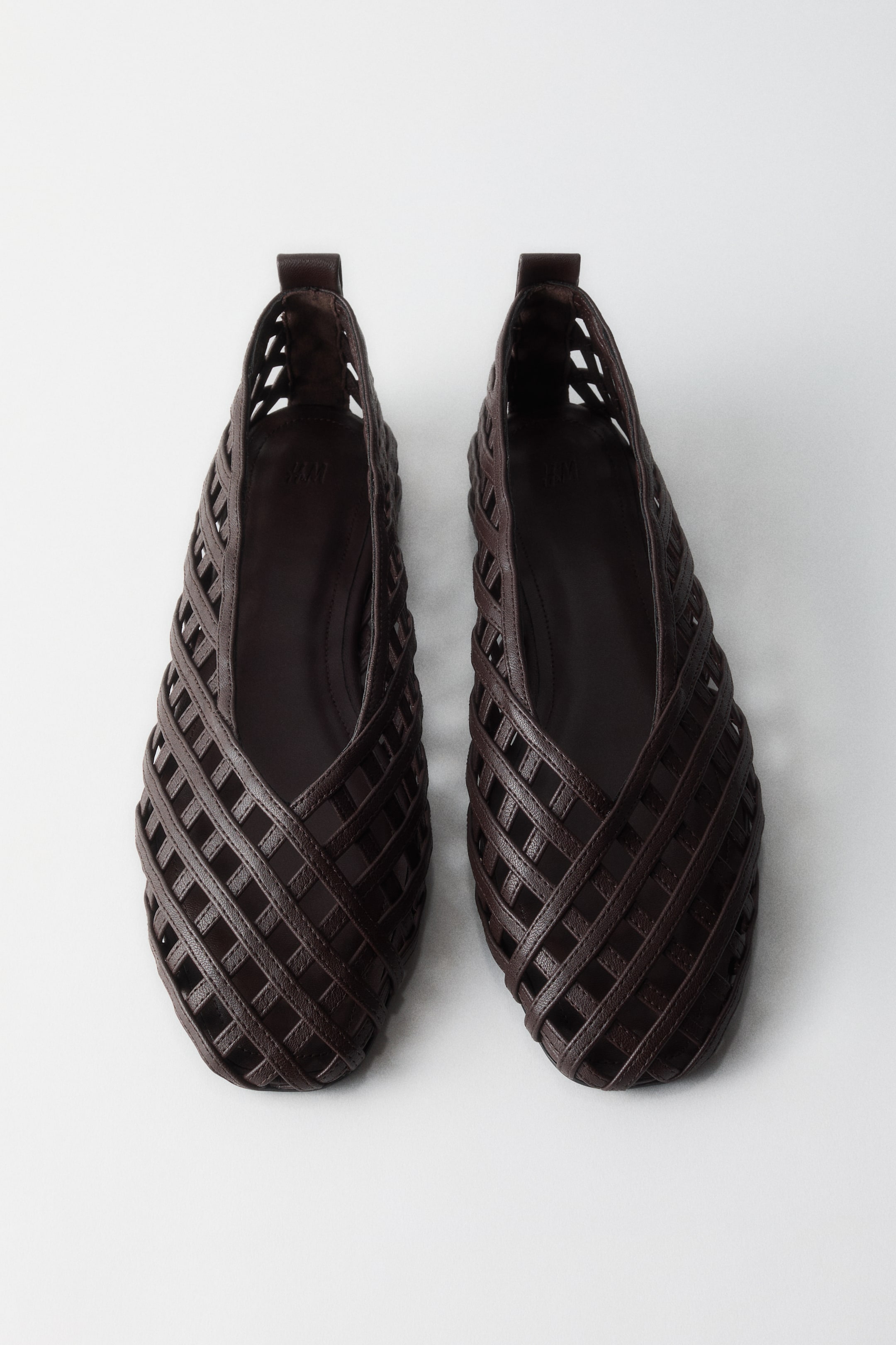 查看大圖: 兩雙深棕色編織皮革平底鞋展示其格子圖案鞋面、深色鞋墊和每個鞋跟的小拉環，兩隻鞋子略微向前和向外傾斜。