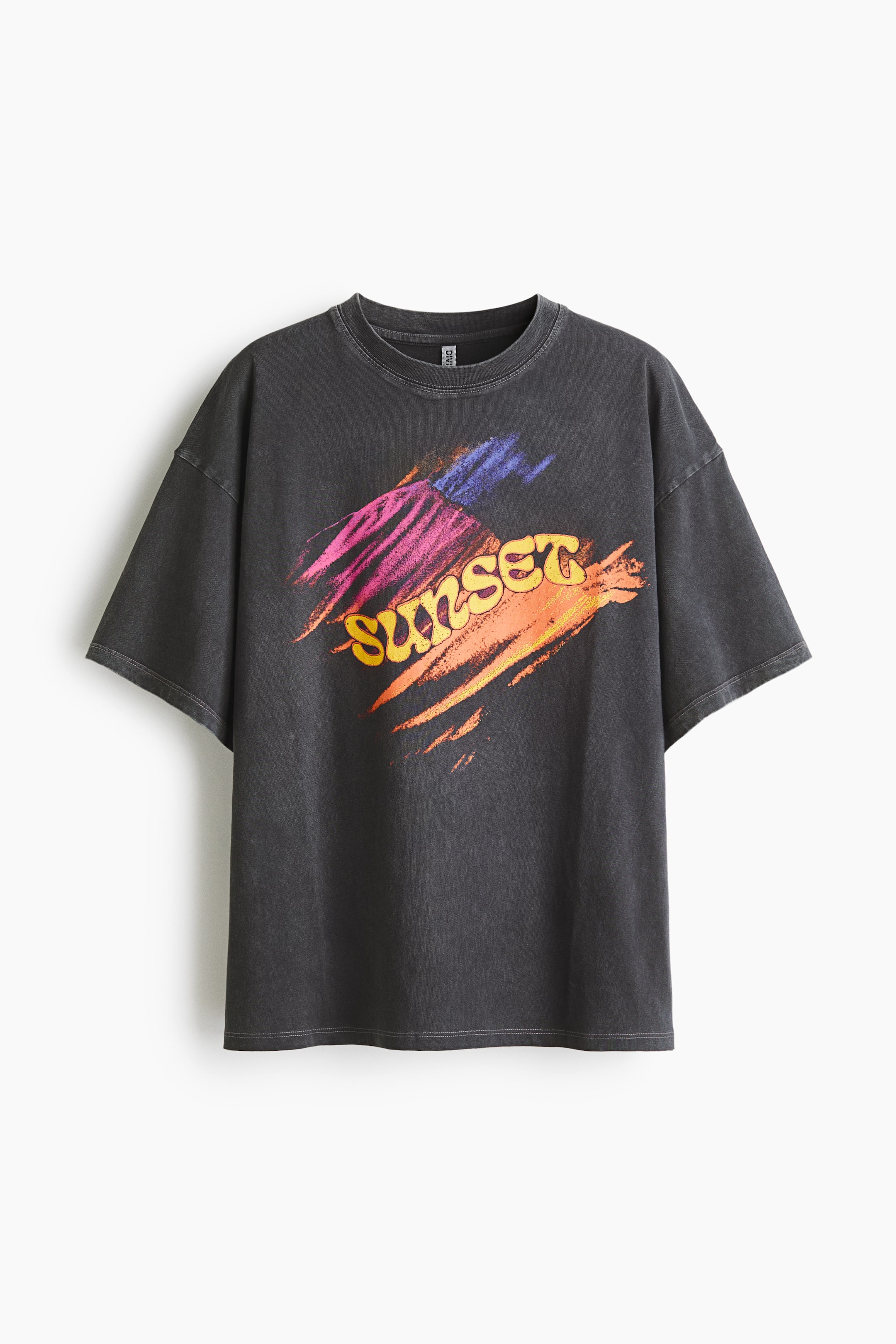 View larger image: An oversized dark grey T-shirt is showcasing its FRONT, featuring a round, rib-trimmed neckline, dropped shoulders, and a straight-cut hem. The chest displays a graphic print of the word 'SUNSET' in yellow and orange, surrounded by brushstrokes in pink, purple, blue, and orange.