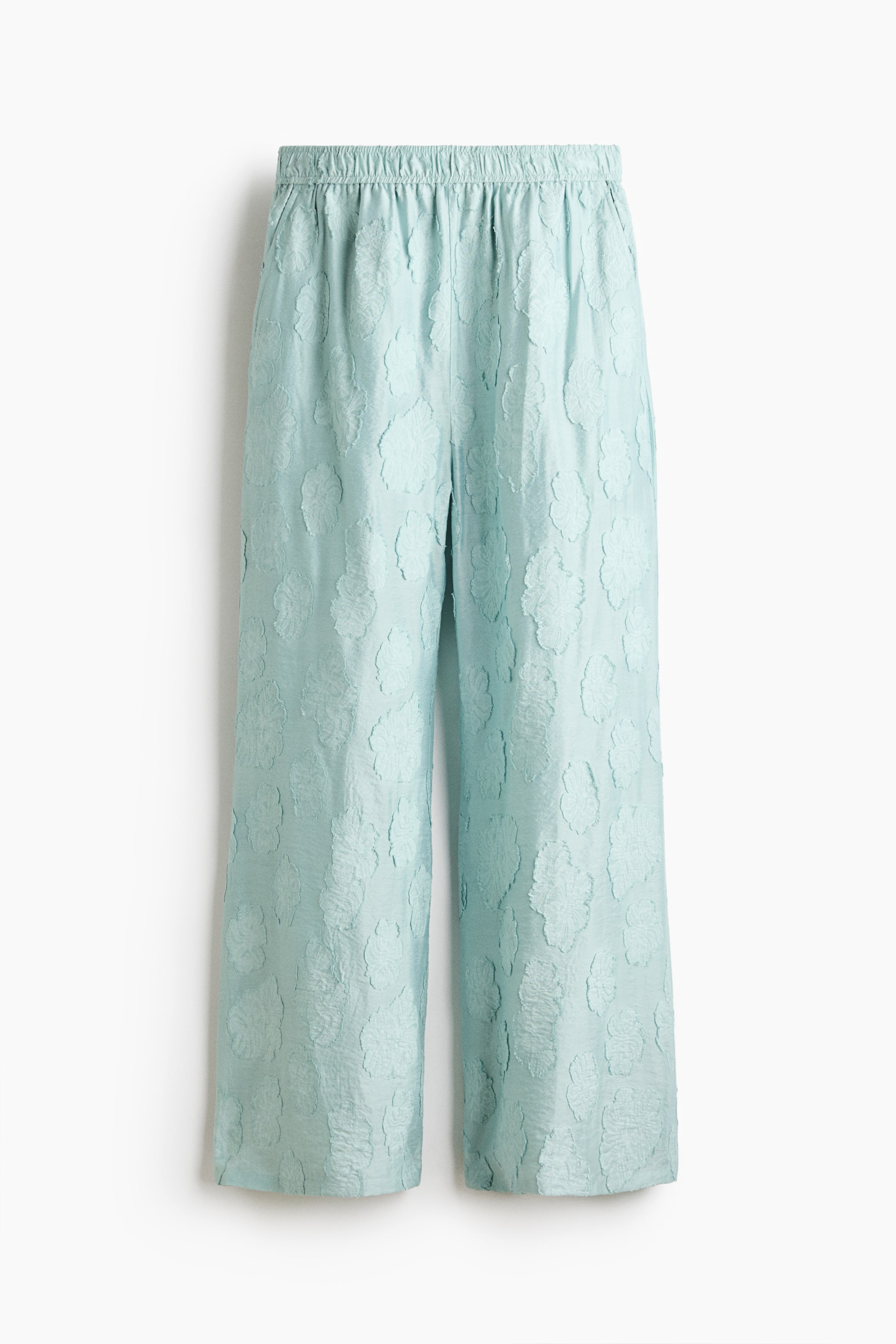 View larger image: Light blue-green cropped pants feature a textured floral pattern throughout. The wide-leg pants showcase an elasticated, ruched waistband and a cropped length.