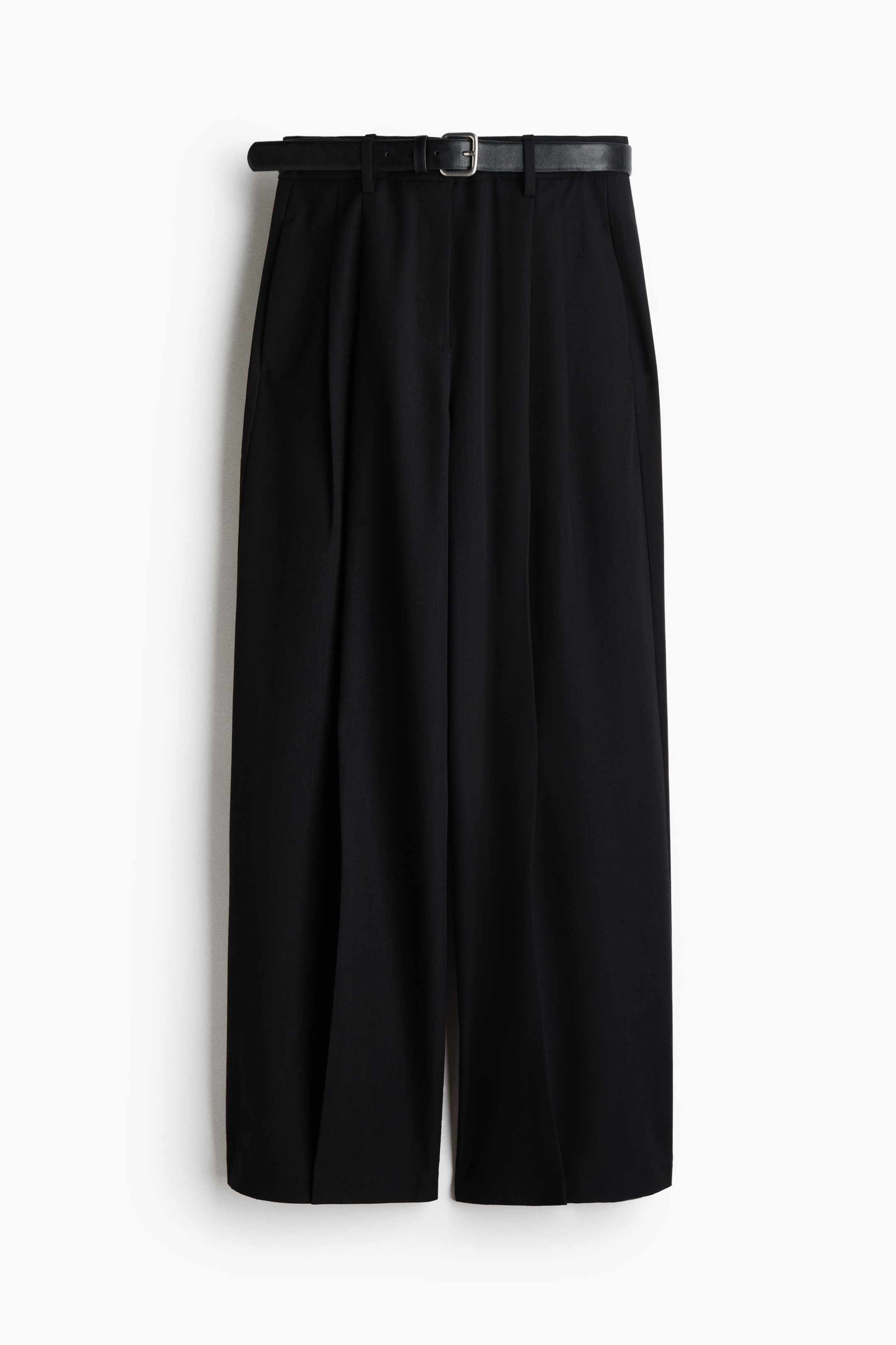 Ampliar la imagen: Pantalones negros mostrados de frente, con una silueta de pierna ancha y corte cropped. Están diseñados con cintura alta y pinzas frontales, e incluyen un cinturón negro con hebilla plateada pasado por las trabillas. Se observan bolsillos laterales.