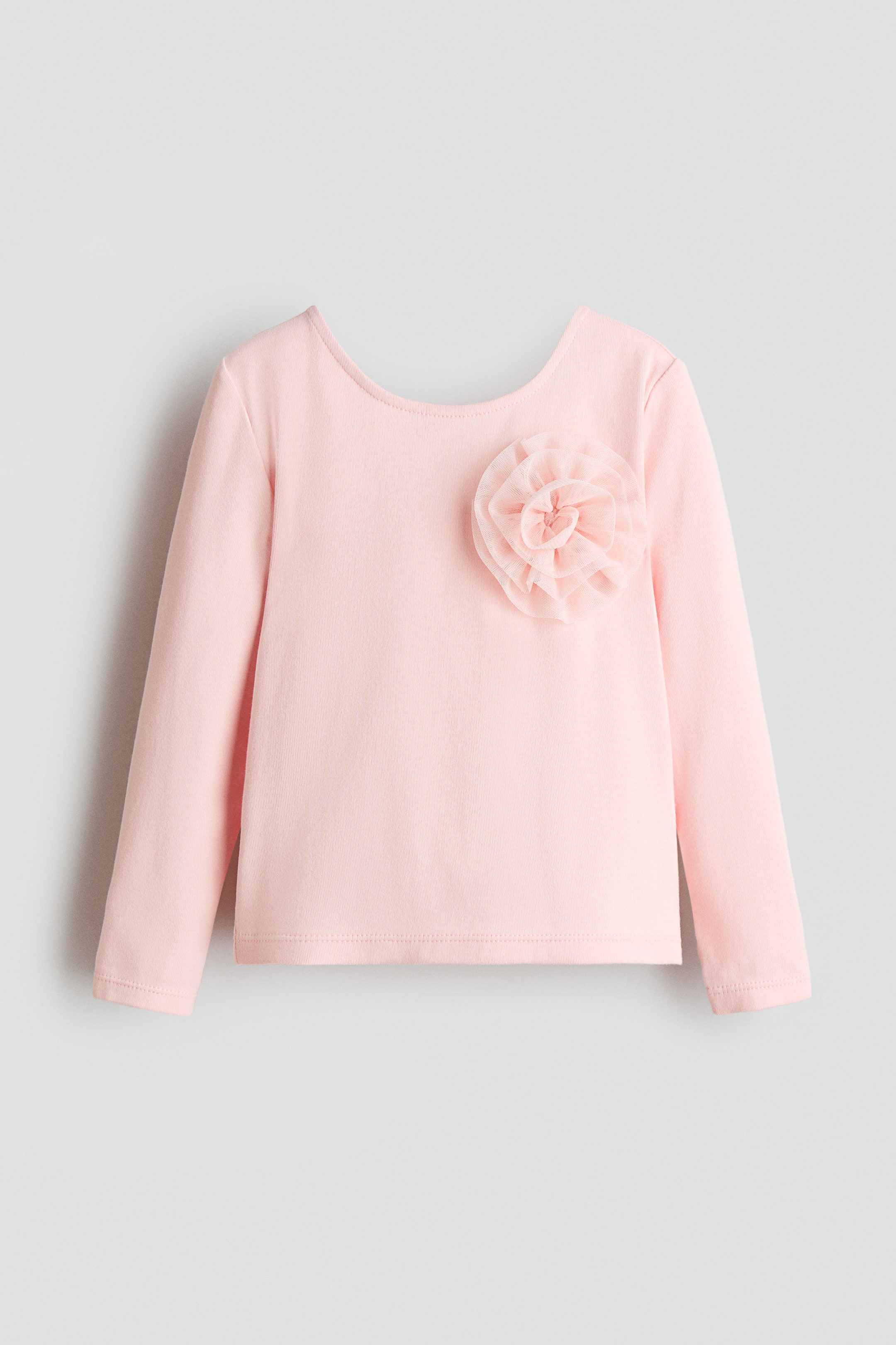 הצגת תמונה גדולה יותר: חולצת שרוול ארוך בצבע ורוד מוצגת מלפנים, עם מפתח צוואר עגול ורחב ופרח מבד בשכבות עם קפלים הממוקם בחלק העליון השמאלי של החזה.