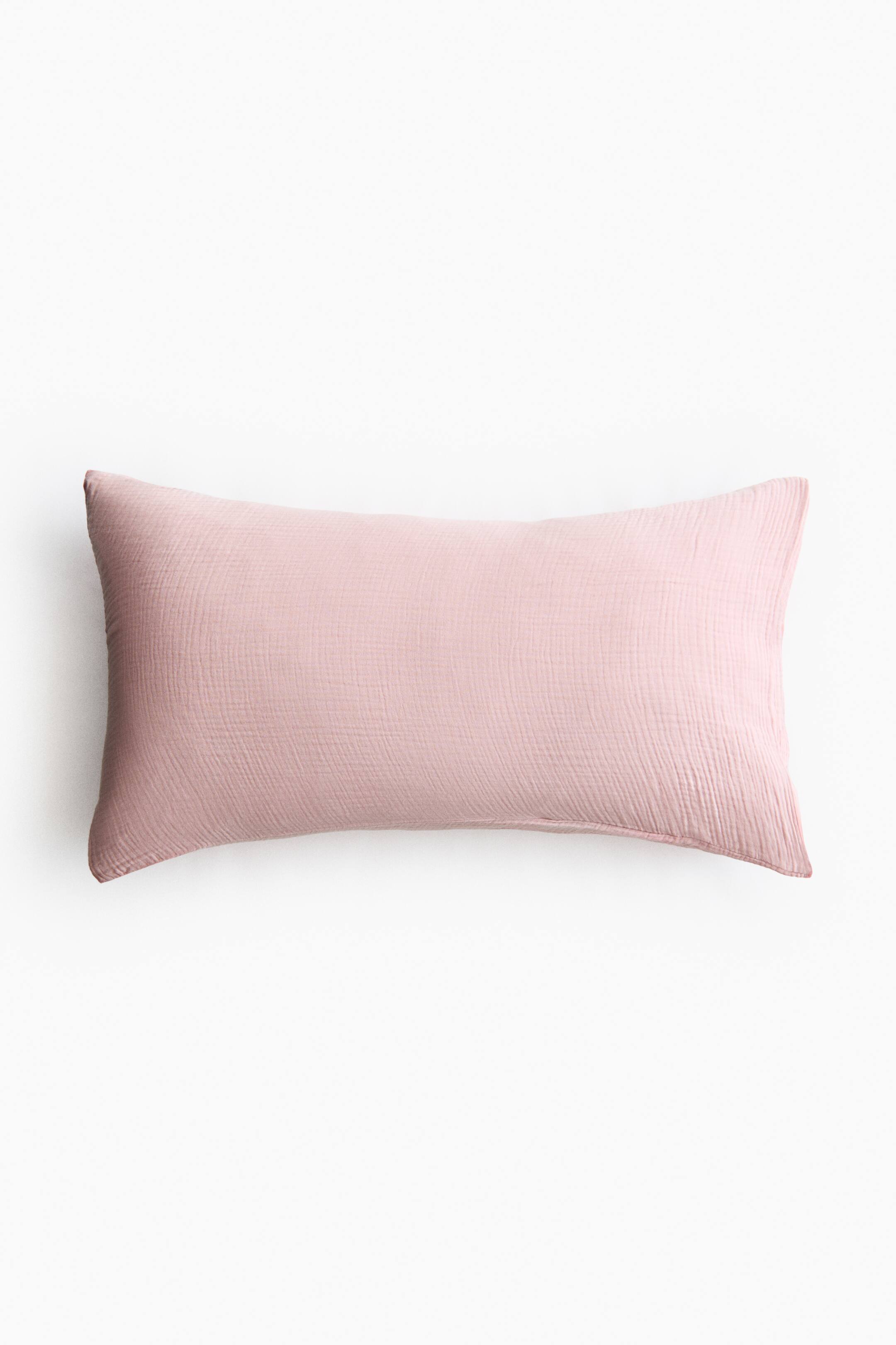 拡大画像を表示: ピンクのコットンモスリン枕カバーは、その前面を見せており、控えめにしわのある質感があります。