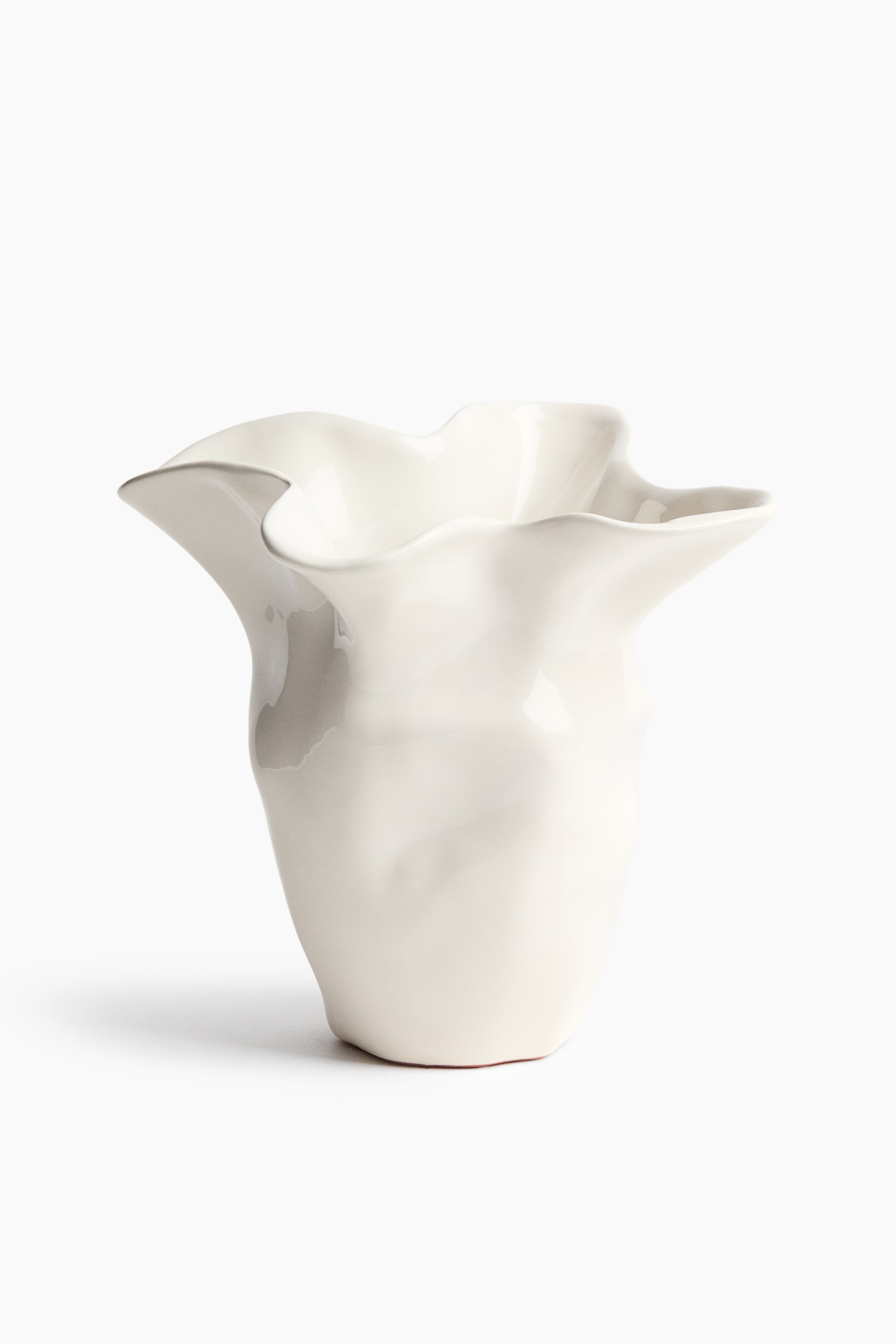 View larger image: A white ceramic vase stands upright, showcasing a wide, undulating rim with a ruffled, organic shape that flares outwards. The vase features a glossy glazed finish and a subtly textured, uneven body.