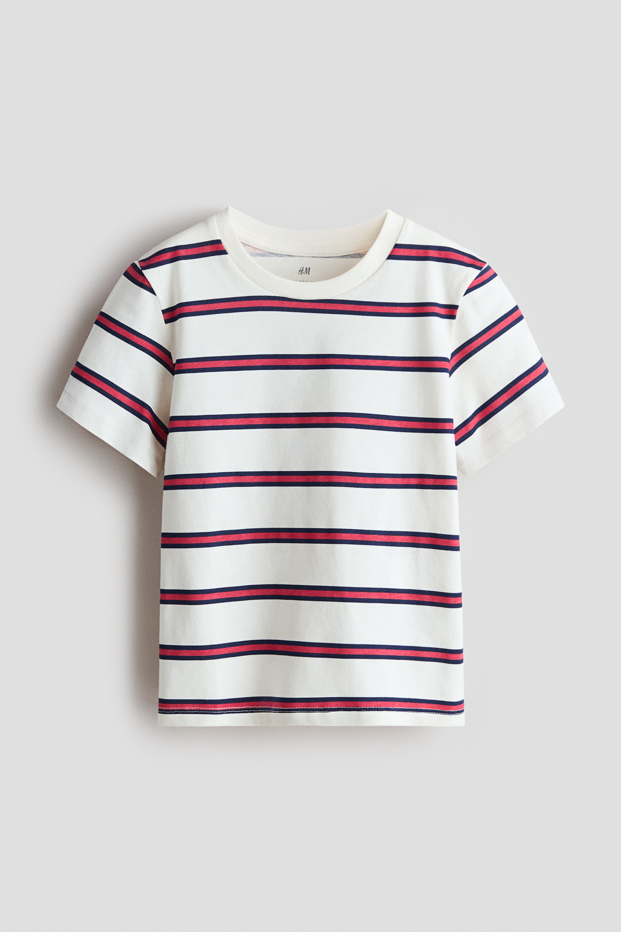 View larger image: The t-shirt showcases its front, crafted from soft, printed cotton jersey. It features a round, ribbed neckline, subtly dropped shoulders, and horizontal stripes in off-white, navy blue, and red.