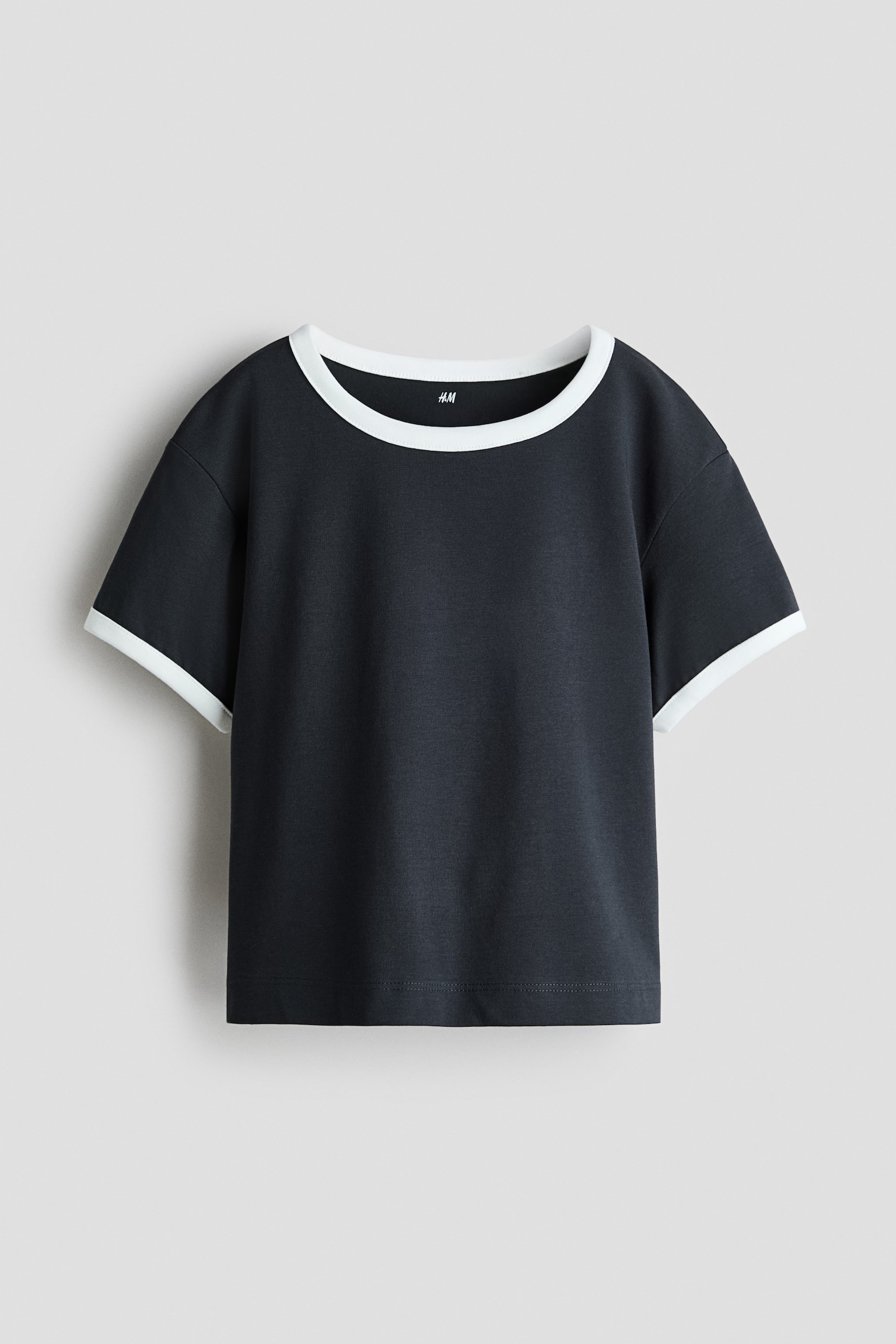 A dark grey ringer t-shirt is shown from the front, featuring a contrasting white crew neck and matching white trim on the short sleeves. The shirt has a relaxed, boxy fit with a straight hem. - 1