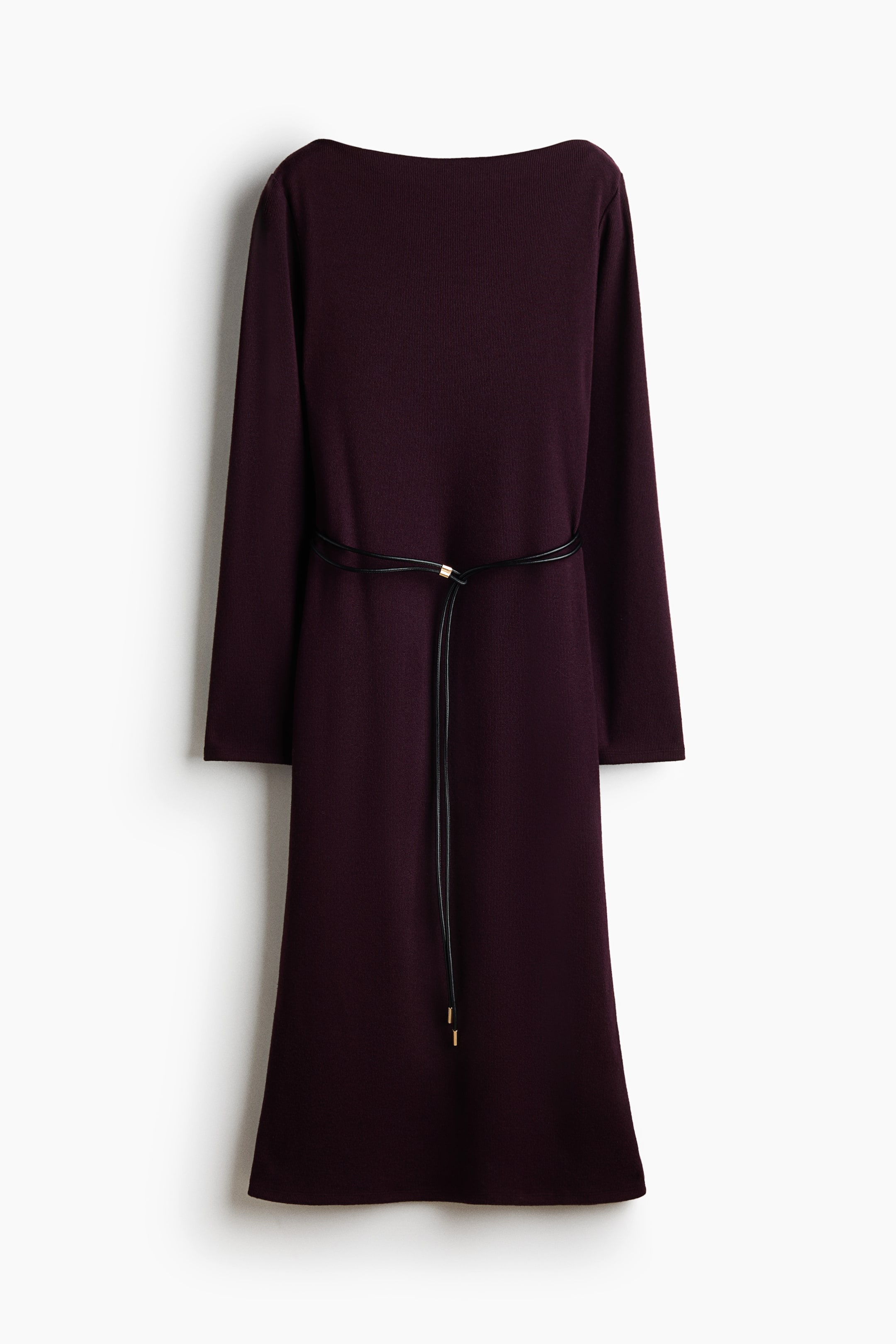View larger image: A deep plum-coloured knit dress is shown from the front, featuring a boat neckline and long sleeves. A thin black double-cord belt with gold-tone metal tips cinches the waist of the straight-cut silhouette.
