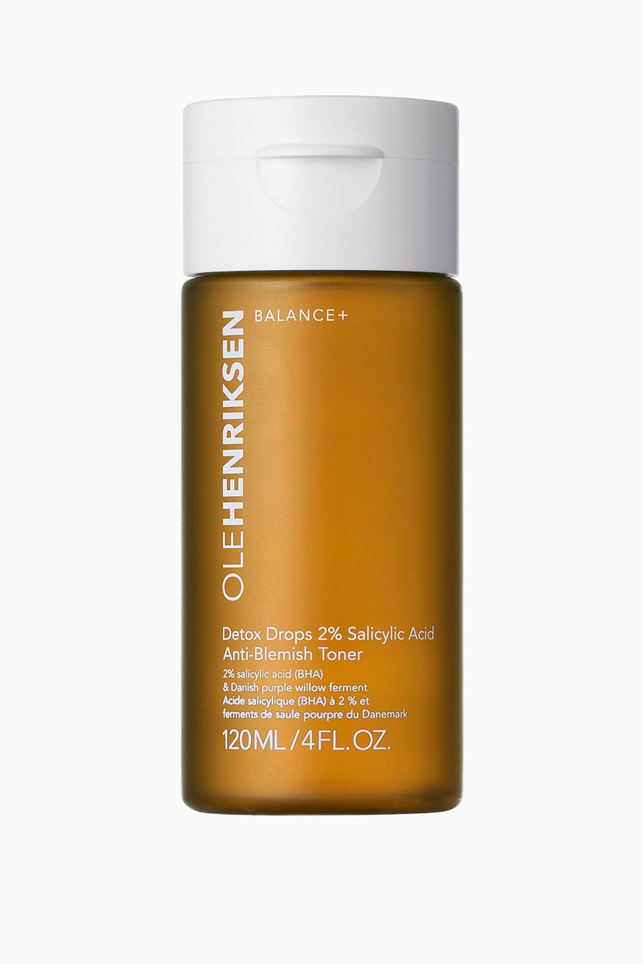 Visa större bild: En Ole Henriksen Balance+ Detox Drops Anti-Blemish Toner visas i sin bärnstensfärgade cylindriska flaska med vit flip-top-kork, vänd framåt. Frontetiketten visar ”OLEHENRIKSEN” vertikalt till vänster, ”BALANCE+” uppe till höger samt produktnamnet ”Detox Drops 2% Salicylic Acid Anti-Blemish Toner” tillsammans med ”120ML / 4FL.OZ.” i vit text.