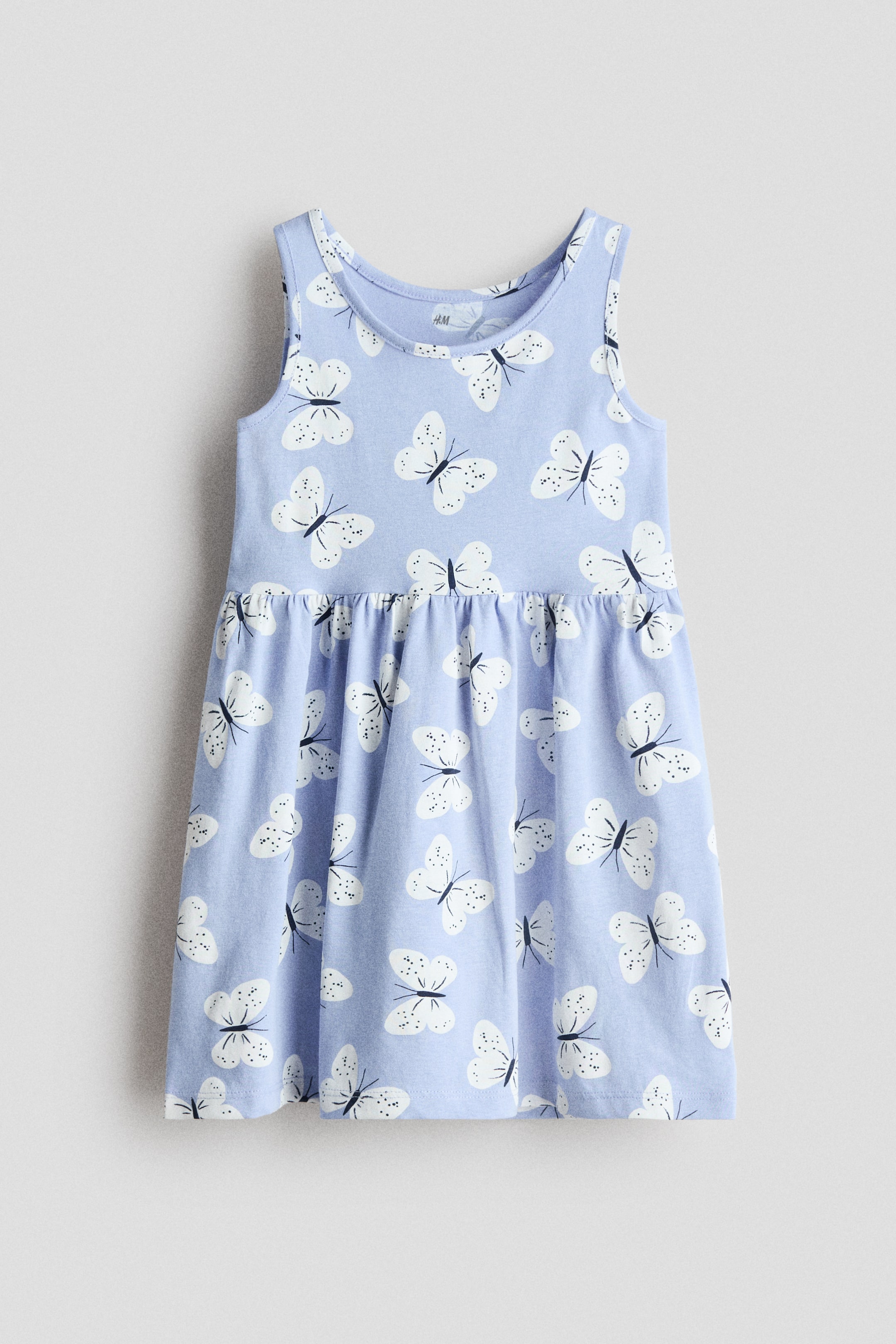 Größeres Bild anzeigen: Ein ärmelloses Kleid wird von vorne präsentiert, bestehend aus einem hellblauen Stoff mit einem weißen Schmetterlingsmuster. Es ist mit einem runden Halsausschnitt, einer gerafften Naht an der Taille und einem sanft ausgestellten Rock designt.