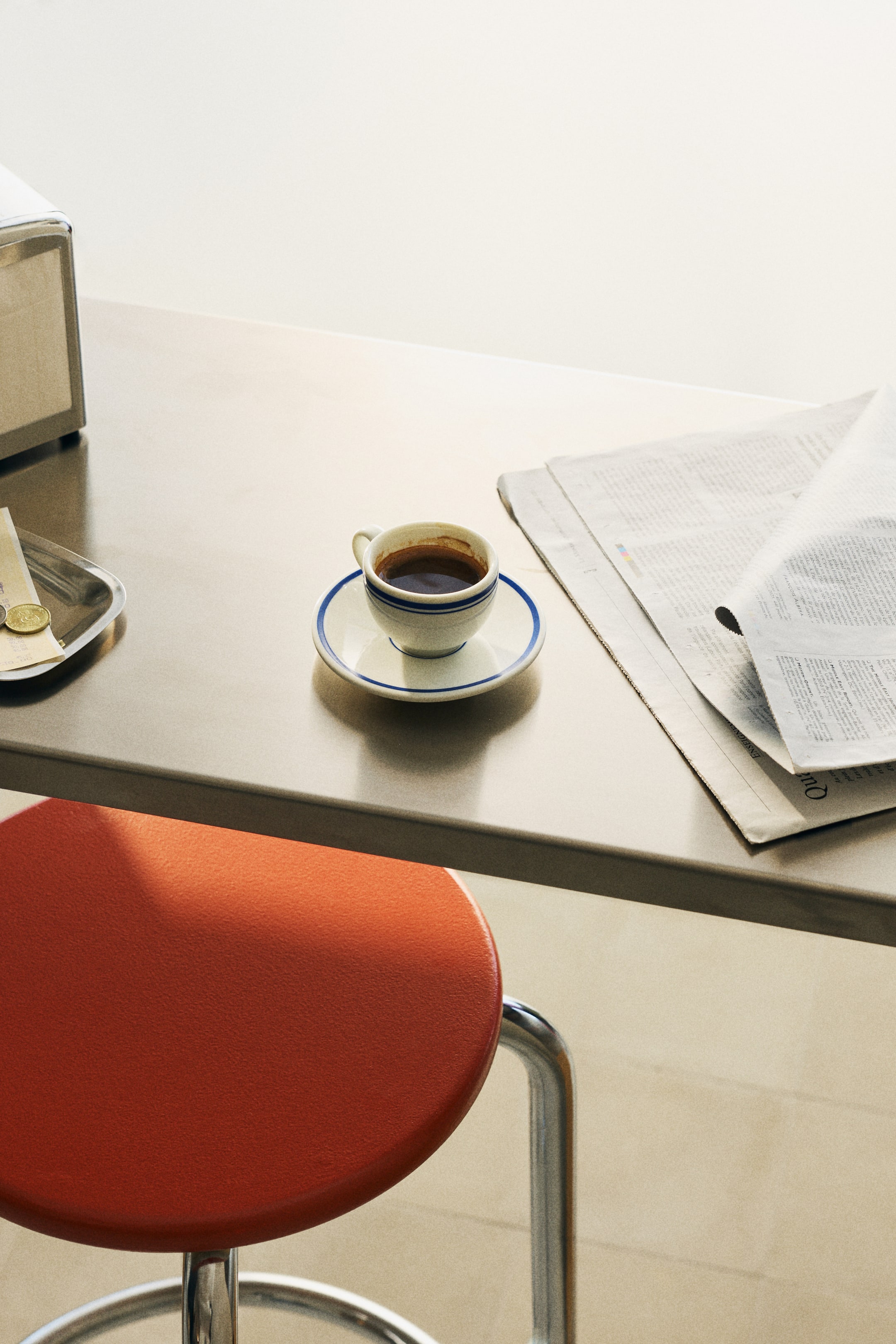 Agrandir l'image: Une tasse à café blanche avec des rayures horizontales bleues repose sur une soucoupe assortie, remplie de café noir. La tasse et la soucoupe sont vues d'un angle légèrement surélevé, orienté vers le bas.
