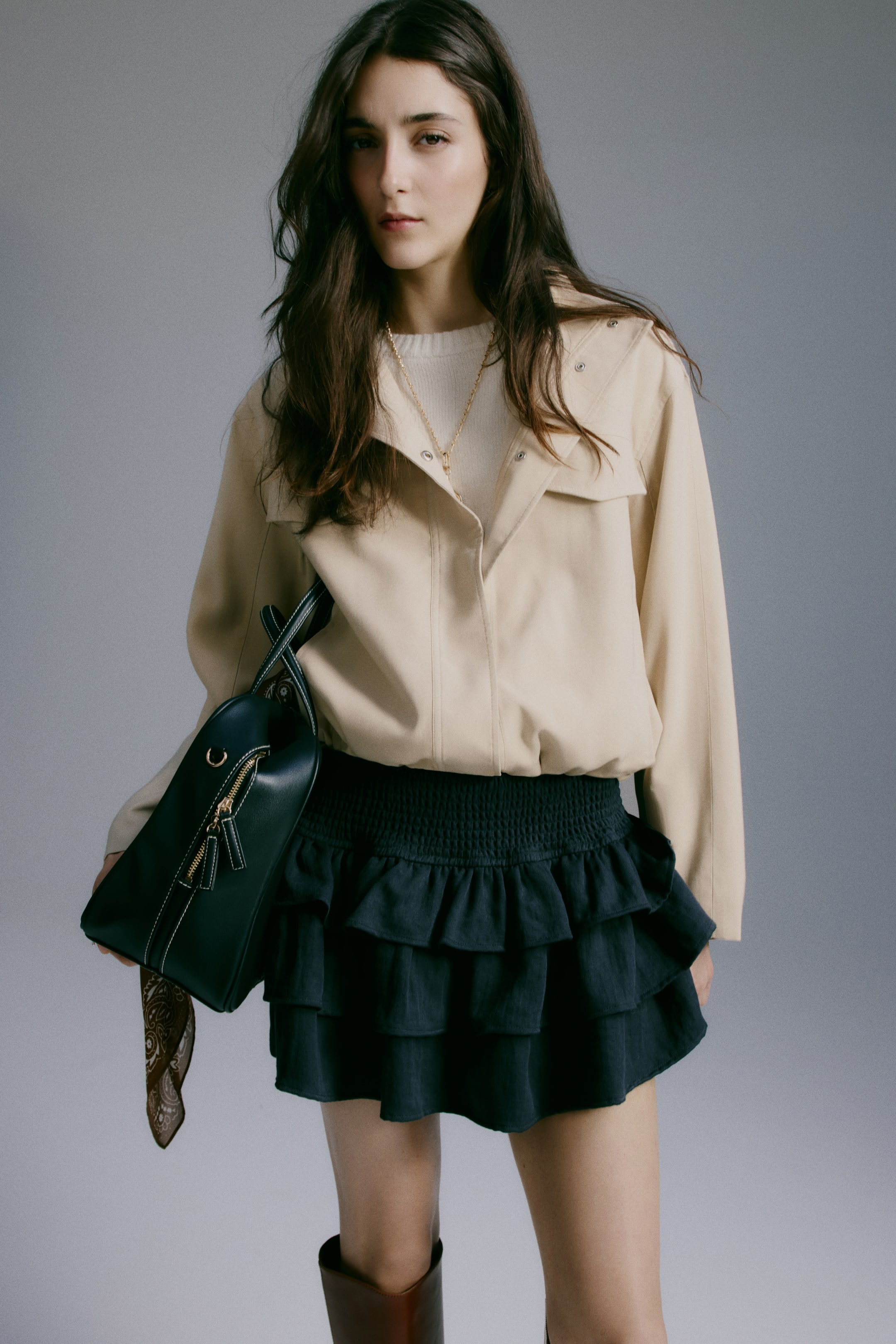 Xem ảnh lớn hơn: Chân váy mini màu tối có phần cạp rộng xếp ly và ba tầng bèo nhún khác biệt, được trình bày từ góc nhìn phía trước.