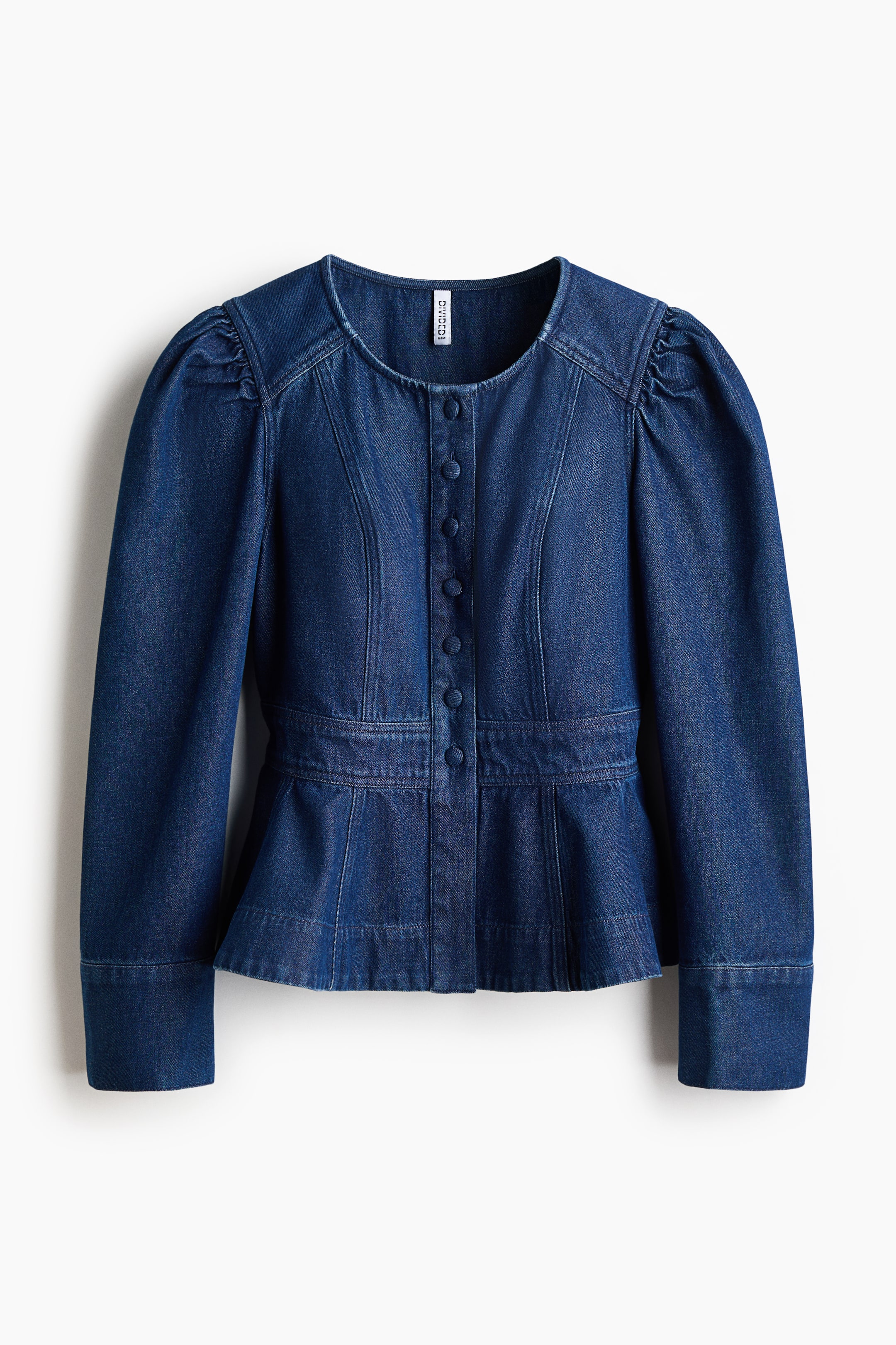 View larger image: A dark blue denim jacket is shown from the front, featuring a collarless round neckline, a button-down front with fabric-covered buttons, and long puff sleeves with wide cuffs. The jacket highlights structured vertical seams along the bodice that taper into a defined waistband and flare out into a peplum hem.