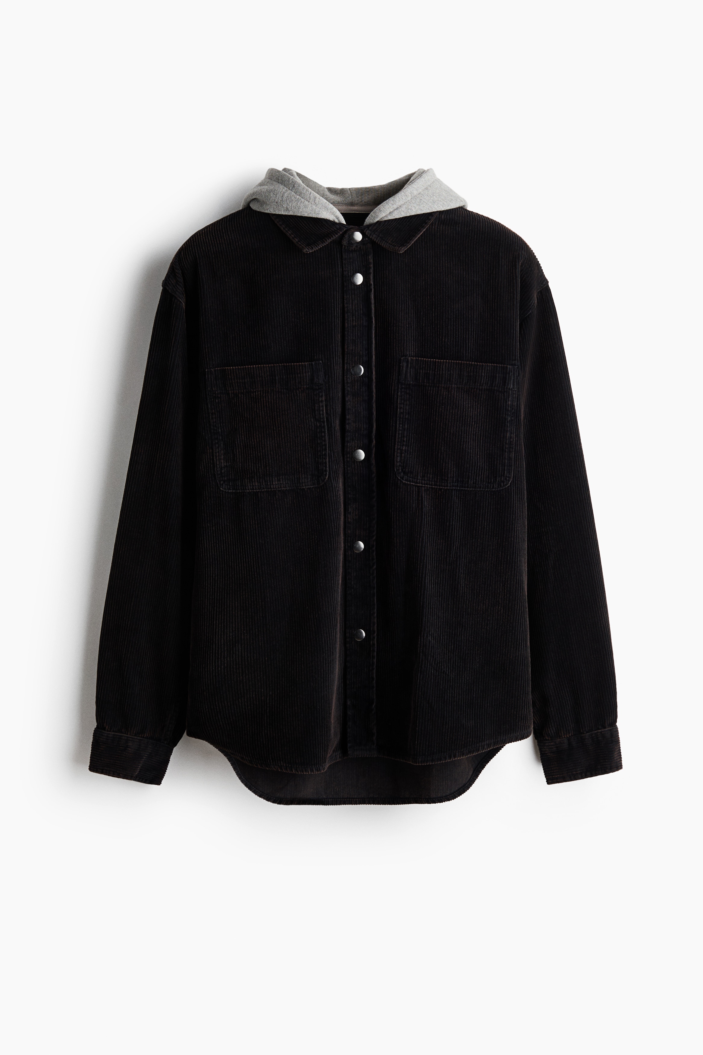Le mannequin porte une surchemise en velours cÃ´telÃ© de coton marron foncÃ©, portÃ©e par-dessus un T-shirt rayÃ©. La surchemise prÃ©sente une capuche contrastante en jersey gris, un col classique, des boutons-pression argentÃ©s sur le devant et deux poches poitrine ouvertes.