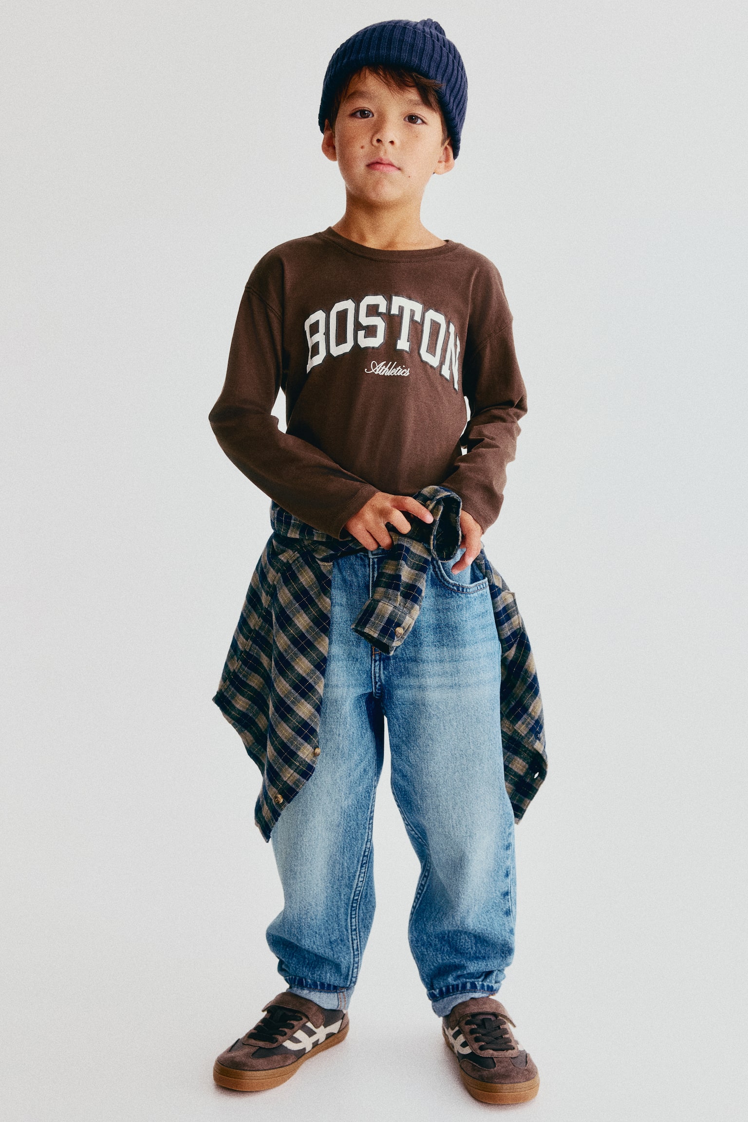 A brown long-sleeved t-shirt is displayed from the front, featuring a ribbed crew neck. The shirt showcases "BOSTON" in large, white, raised appliqué letters across the chest, with "Athletics" in smaller, white, embroidered script text positioned below. - 1