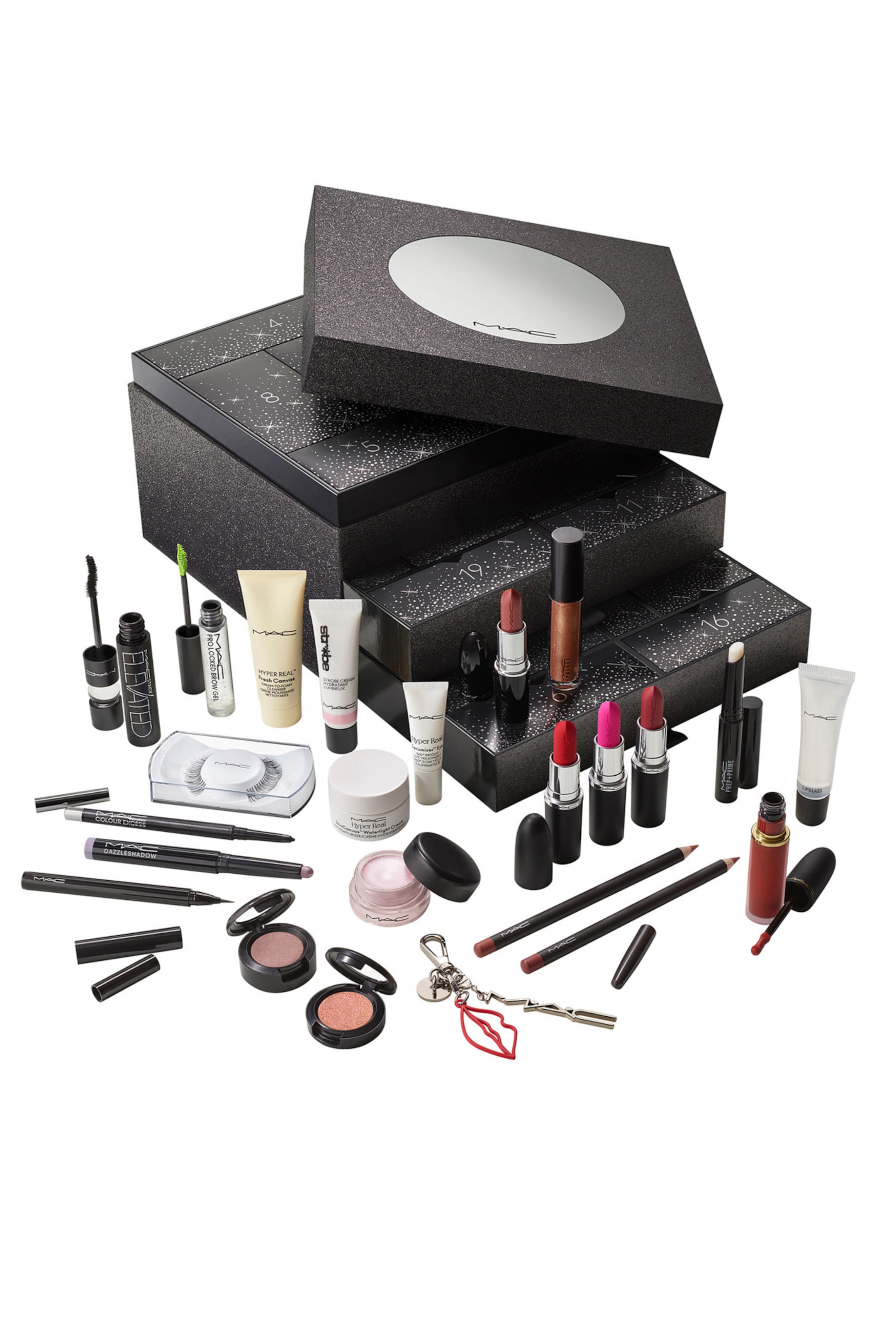 Visa större bild: En flervånings, skimrande svart adventskalenderask visar upp ett urval av MAC cosmetics och hudvårdsprodukter arrangerade i förgrunden. Olika produkter, inklusive läppstift, läppglans, enskilda ögonskuggor, eyeliners och hudvårdstuber, står och ligger framför de öppna, numrerade facken.