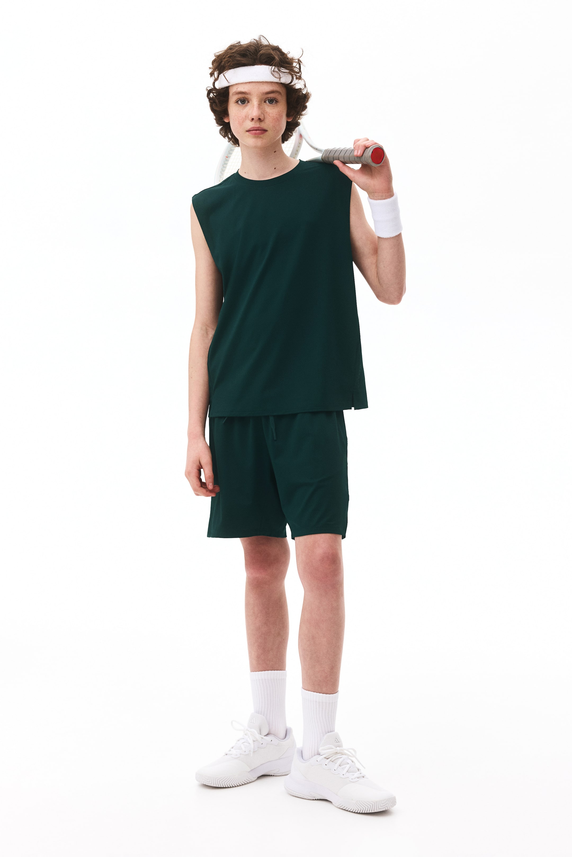 Agrandir l'image: Un ensemble de sport deux pièces avec DryMove? est visible de face. Il se compose d'un haut sans manches vert foncé avec un col rond et une coupe décontractée, assorti à un short vert foncé avec une taille élastique et un cordon de serrage visible, d'une longueur mi-cuisse.