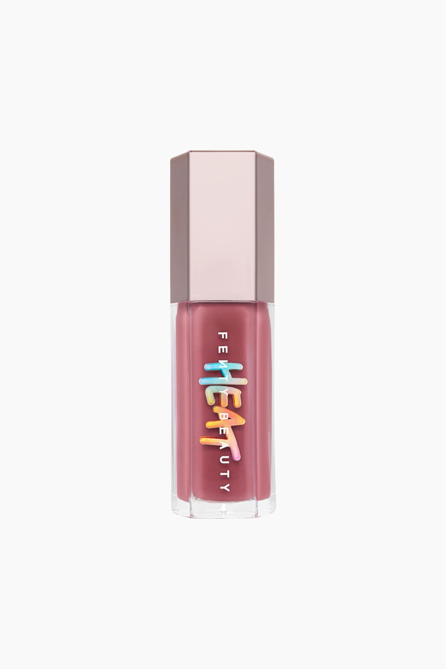 Gloss Bomb Heat Universal Lip Luminizer + Plumper stÃ¥r oprejst og har et gennemsigtigt sekskantet hylster fyldt med en stÃ¸vet rosa gloss og afsluttet med en metallisk rosaguld sekskantet hÃ¦tte. Forsiden af beholderen viser det lodrette hvide "FENTY BEAUTY"-brandnavn, overlejret med en stiliseret, dryppende "HEAT"-grafik i en flerfarvet gradient. - 1