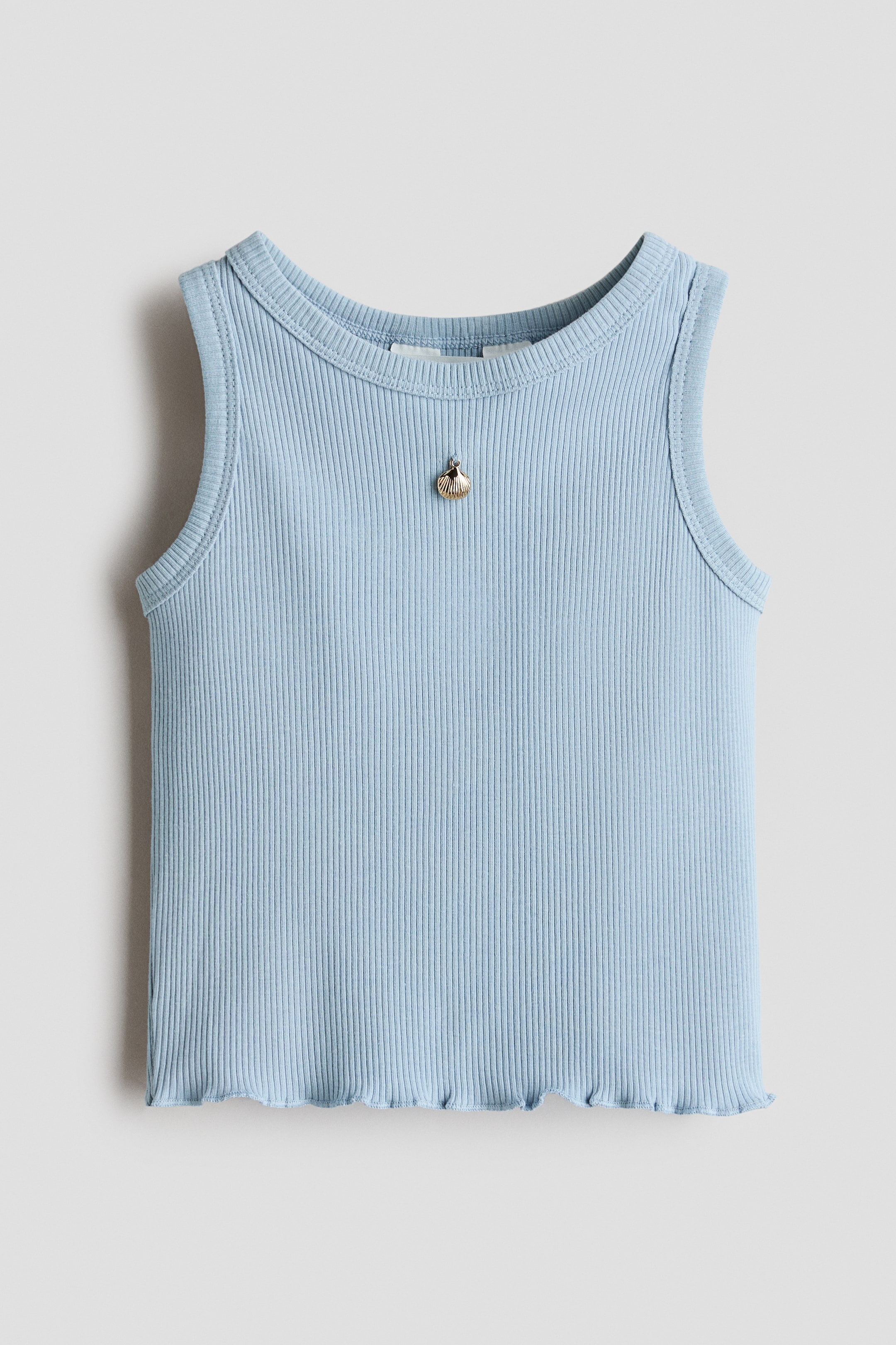 Größeres Bild ansehen: Ein hellblaues geripptes Tanktop liegt flach da, mit einem runden Ausschnitt und einem welligen Saum. Ein kleiner goldfarbener Muschelanhänger ist mittig am vorderen Ausschnitt befestigt.