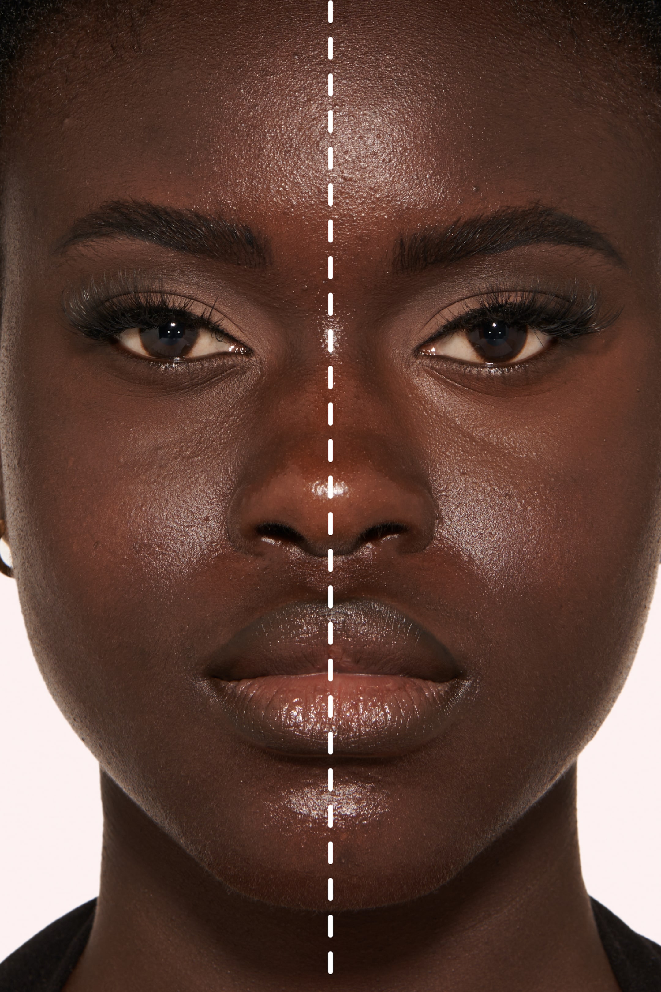 Näytä suurempi kuva: Lähikuva esittelee tumman ihon ihmisen kasvoja, jotka on pystysuunnassa jaettu katkoviivalla. Vasemmalla puolella näkyy luonnollinen ihon rakenne ja hienoinen kiilto, kun taas oikealla puolella on sileämpi, mattapintaisempi iho, määritellyt kulmakarvat, korostetut ripset ja kiiltävät huulet.
