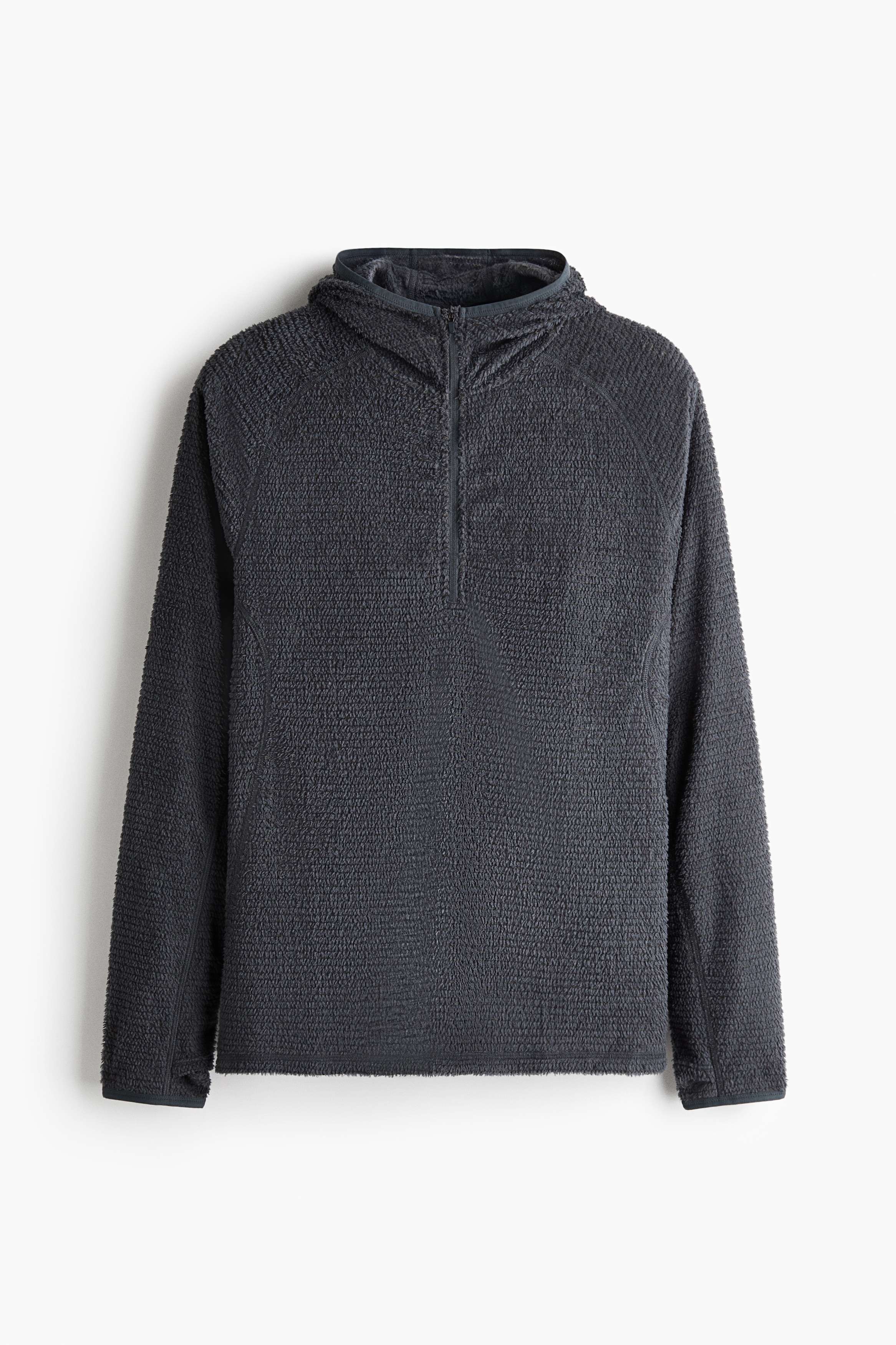 Một chiếc áo hoodie màu xám có họa tiết vân nhám với hoa văn ô lưới mịn đang được người mẫu mặc, được thể hiện ở góc nghiêng. Áo hoodie được phối cùng mũ lưỡi trai màu đen, kính râm tối màu và găng tay màu xám.