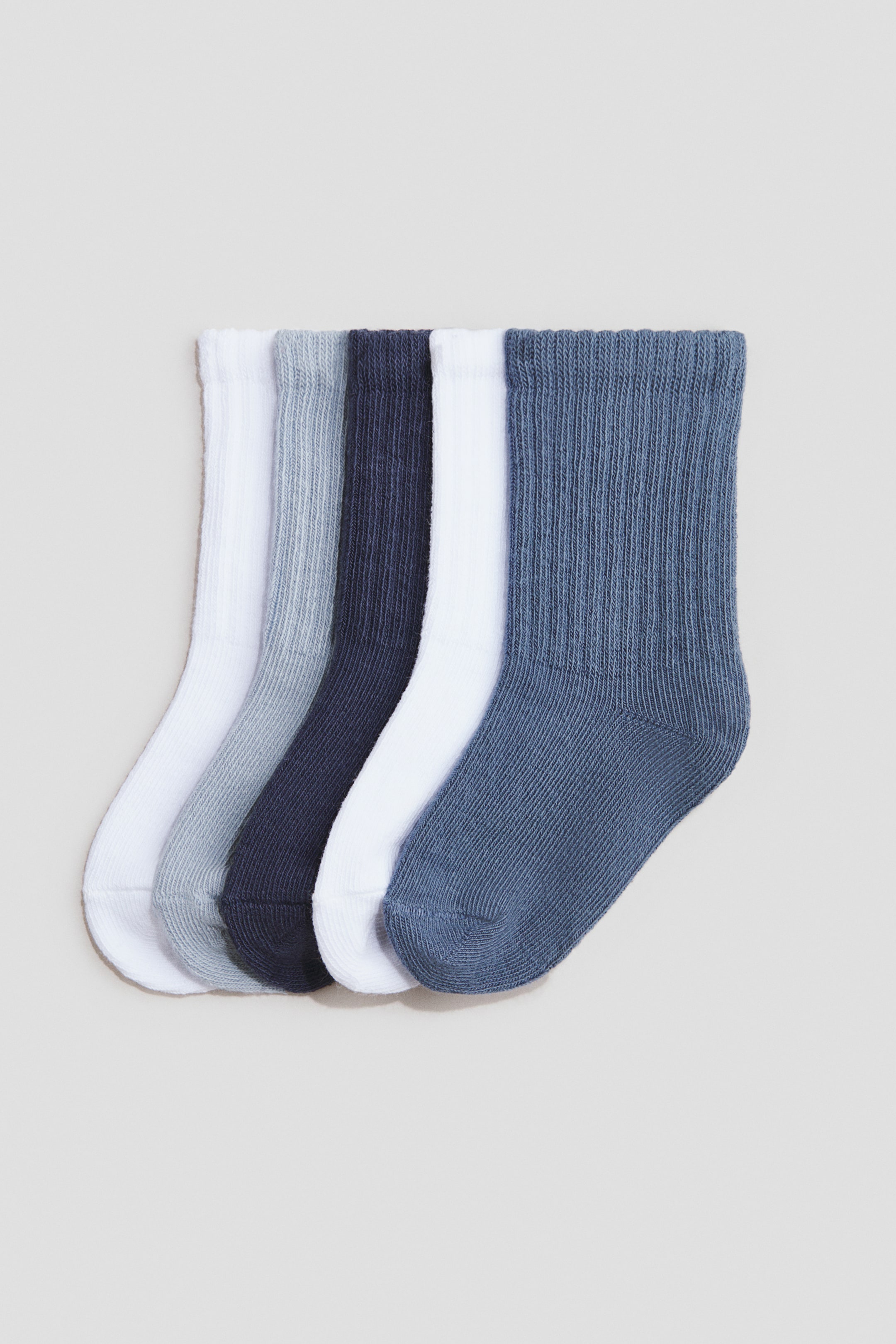 View larger image: Five ribbed crew socks are overlapping and fanned out, showcasing shades of white, light grey, dark blue, white, and medium blue, with their cuffs oriented towards the top left.