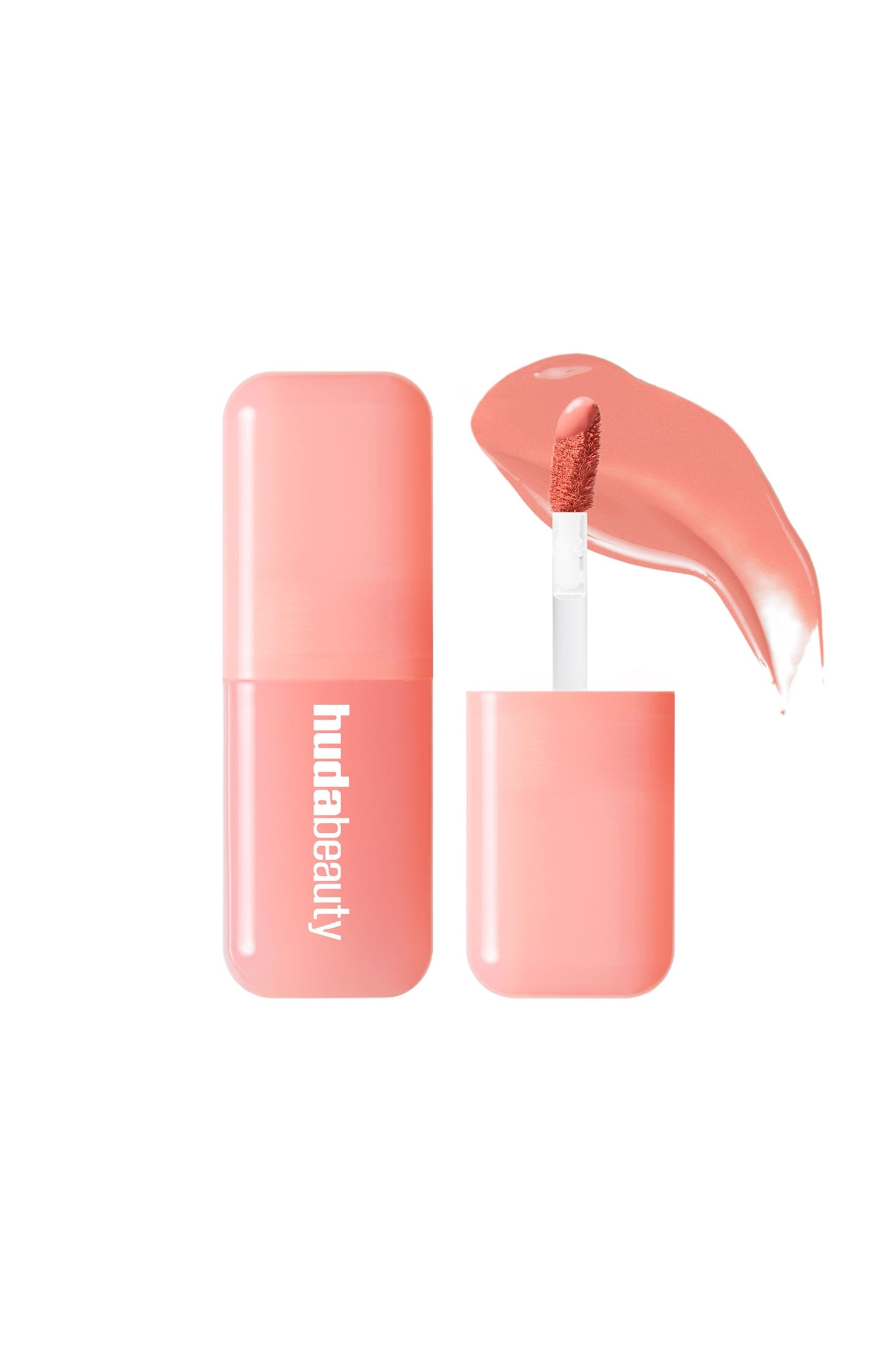 Visa större bild: En Huda Beauty läppglans visas, med ett stängt rektangulärt genomskinligt persikorosa rör med rundade kanter till vänster, där "hudabeauty" står i vit text. Till höger avslöjar det öppna röret en hjortfotapplikator mättad med den persikorosa produkten, från vilken ett glansigt prov sträcker sig ut.