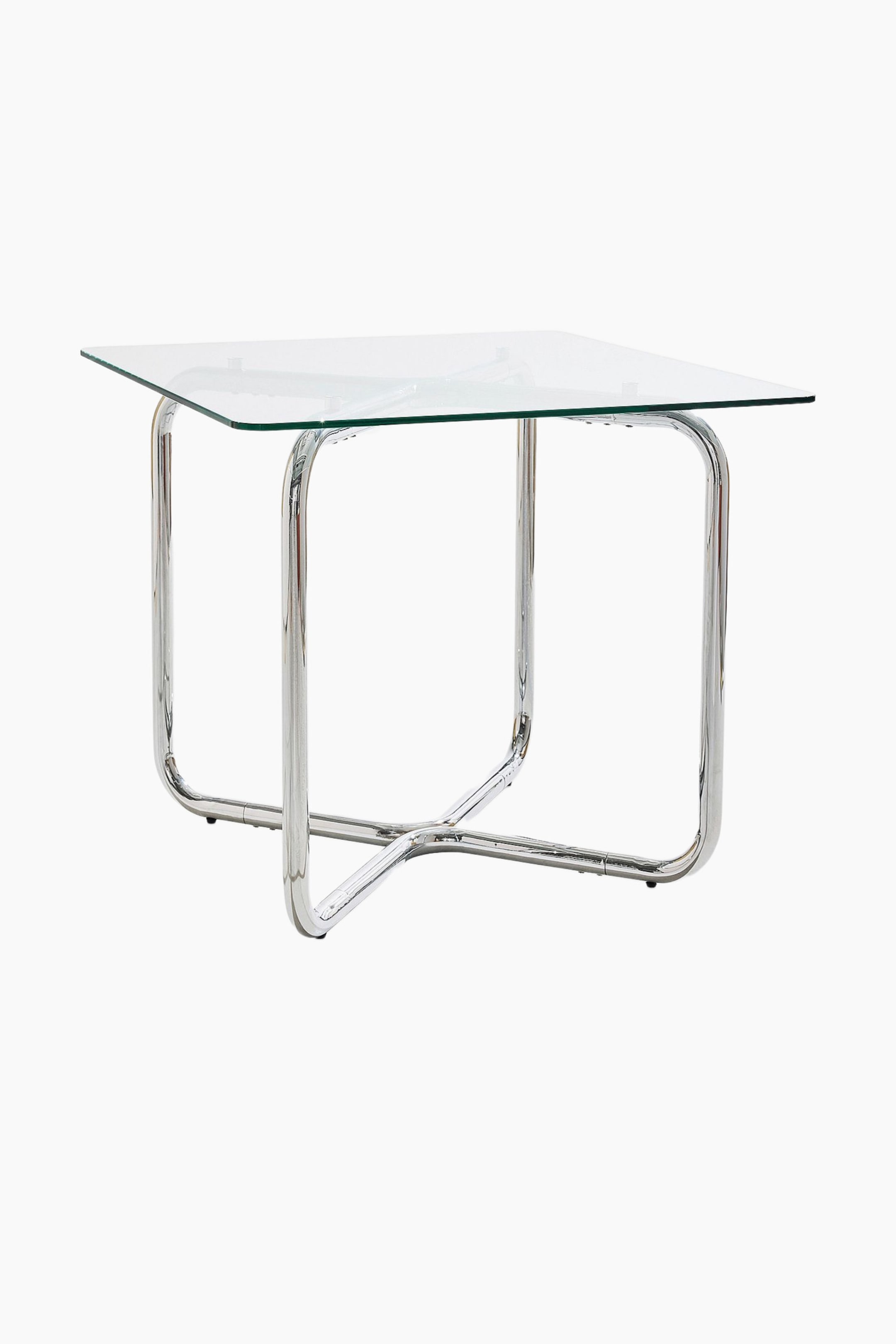 Grotere afbeelding bekijken: Een vierkante tafel met een glazen blad is licht schuin geplaatst, waardoor de verchroomde buisvormige metalen basis zichtbaar wordt. De basis heeft twee U-vormige steunen die onderaan verbonden zijn met een centrale X-vormige dwarsbalk.